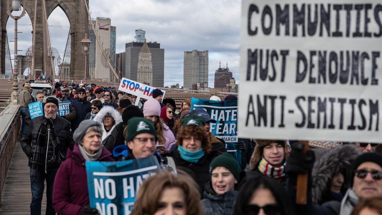 Protesters march across a bridge protesting against hate and antisemitism.