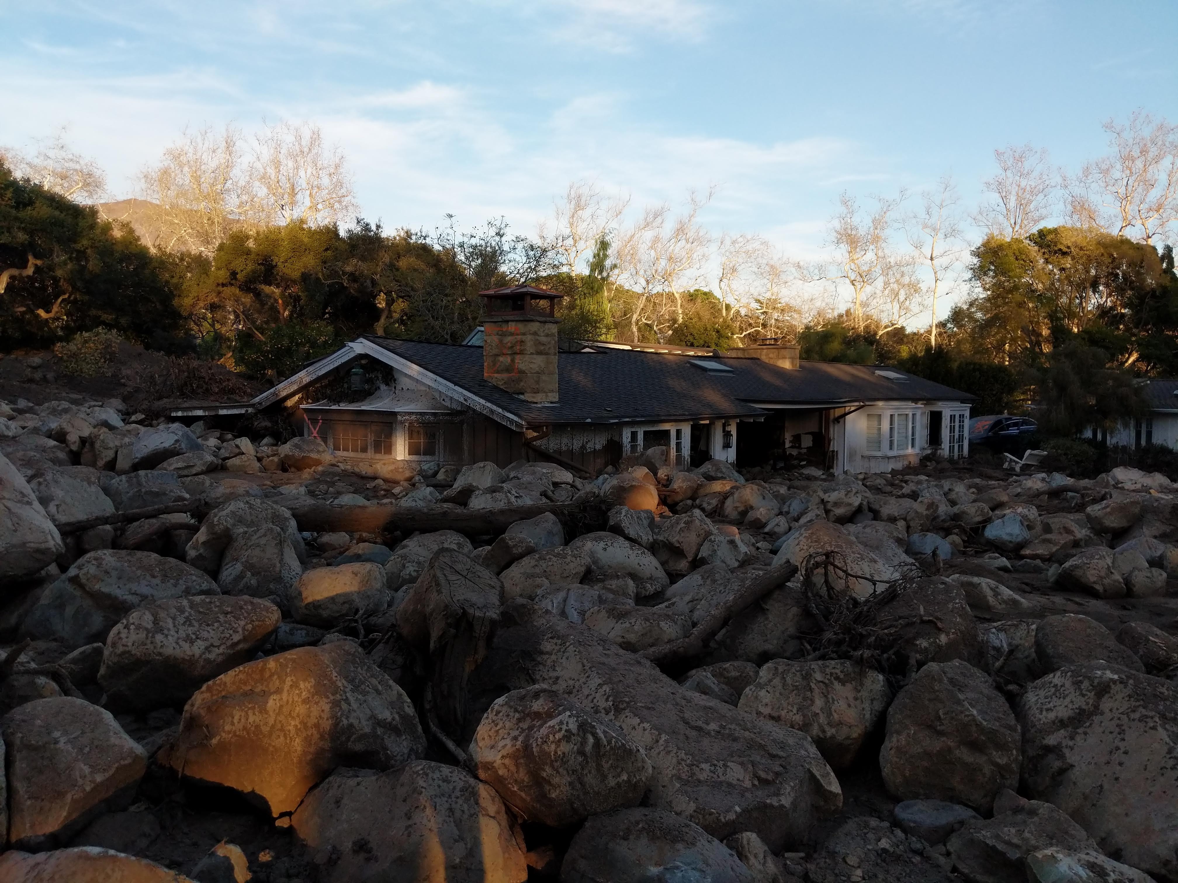 house surrounded by boulders carried by a mudslide