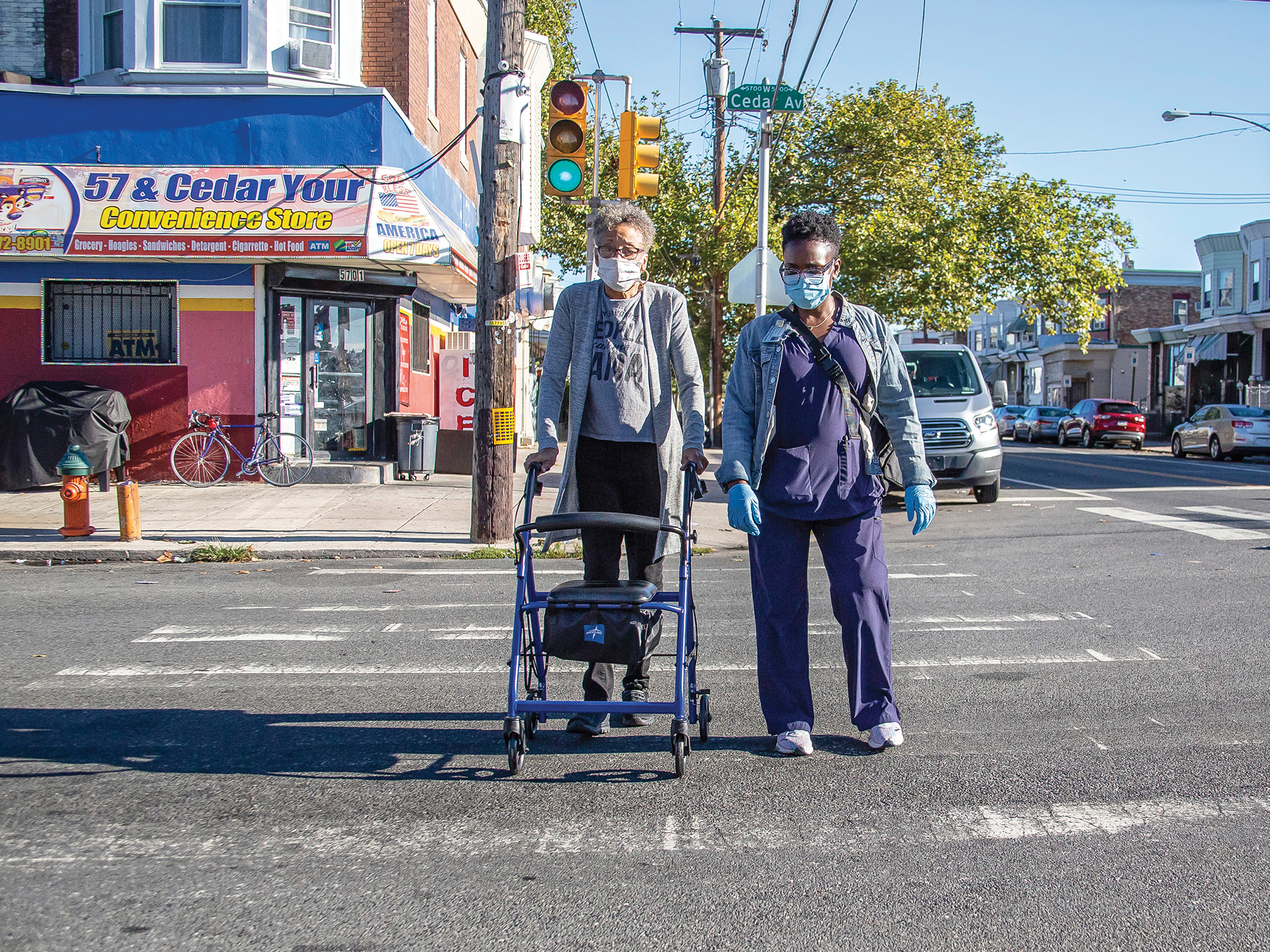 nurse helping elderly person cross the street with a walker