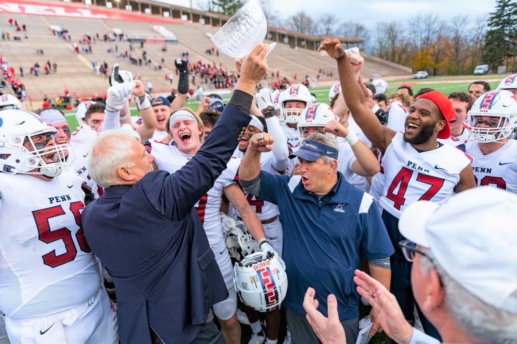 Penn players and coaches celebrate with the Trustees’ Cup after the win.