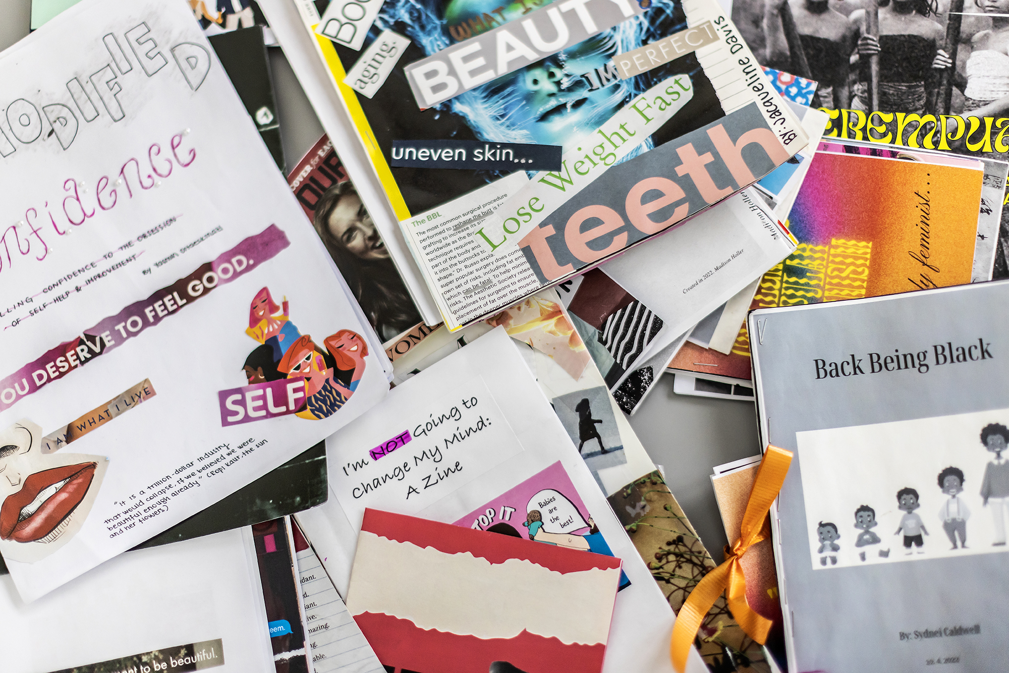 A pile of zines read things like, "uneven skin...," "lose weight fast," and "I'm not going to change my mind."