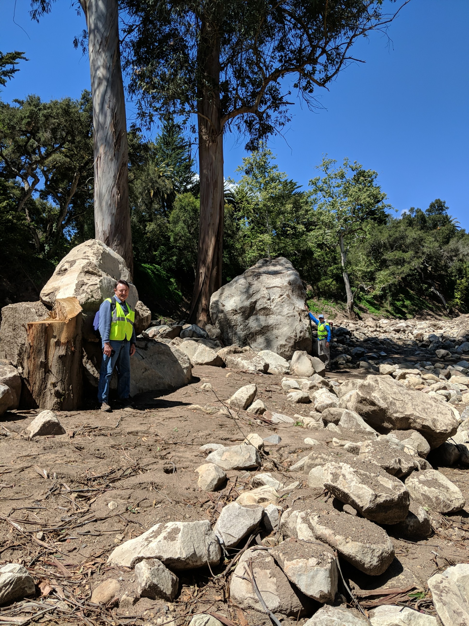 Two scientists stand next to boulders larger than them during field work