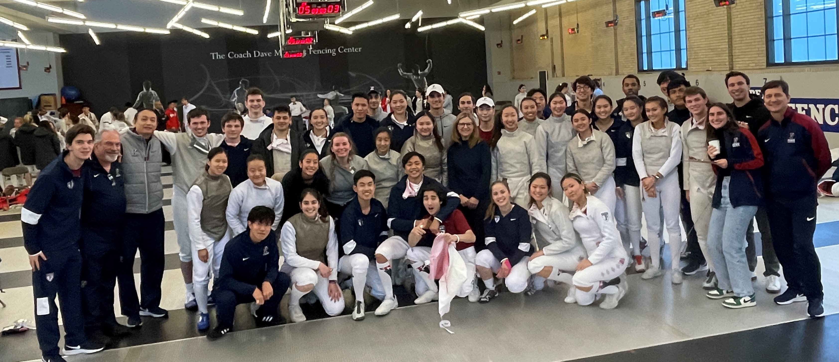 President Liz Magill (second row, center right, in all black) poses with members of the men’s and women’s fencing teams at the Elite Invitational.