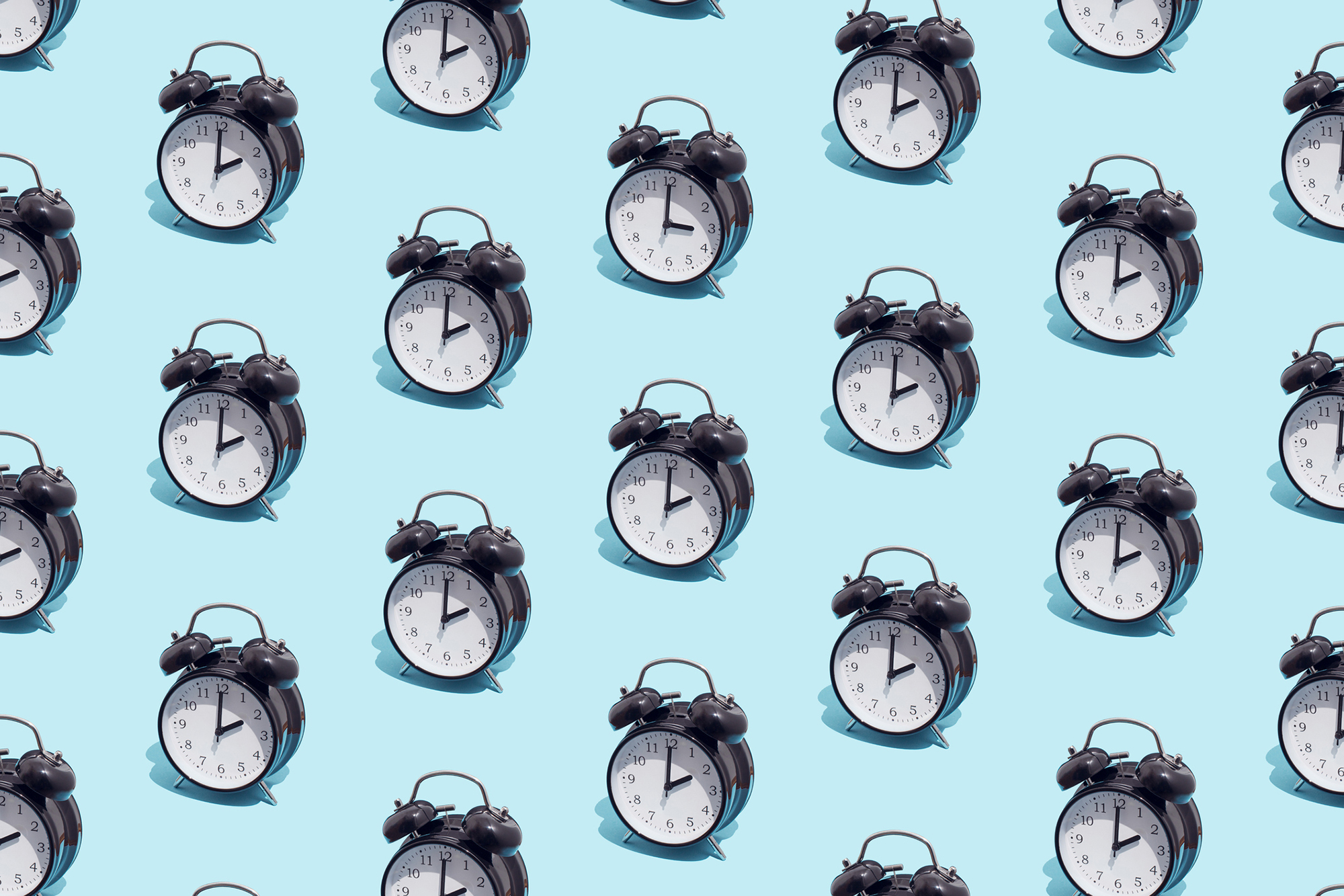 Pattern of black retro alarm clocks show 2 o'clock and one shows 3 o'clock