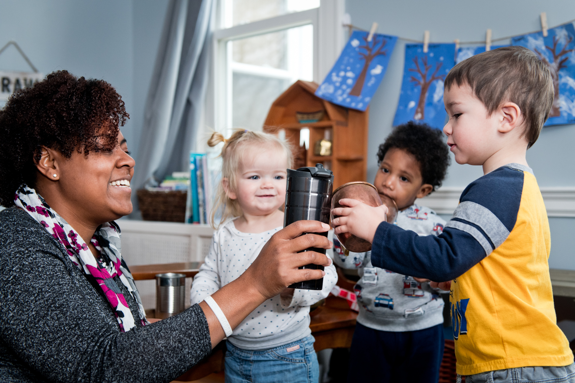 An image of a caregiver "toasting" mugs with a toddler