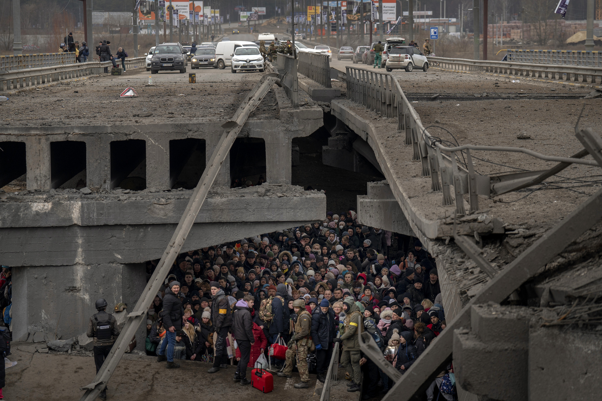 Ukrainians huddle under a destroyed bridge as they try to flee by crossing the Irpin River on the outskirts of Kyiv, Ukraine, on March 5, 2022. 