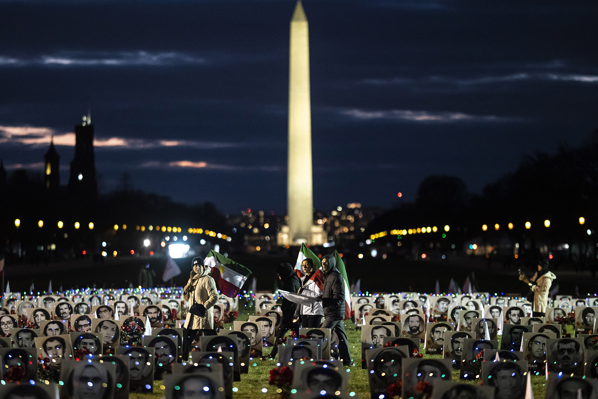 Protesters carrying Iranian flags walk through the National Mall in Washington, D.C., which is dotted with black and white photos of Iranians allegedly killed by their government.