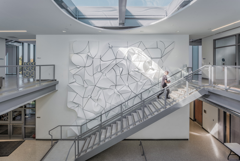 A large two-story wall inside a library beside a staircase.