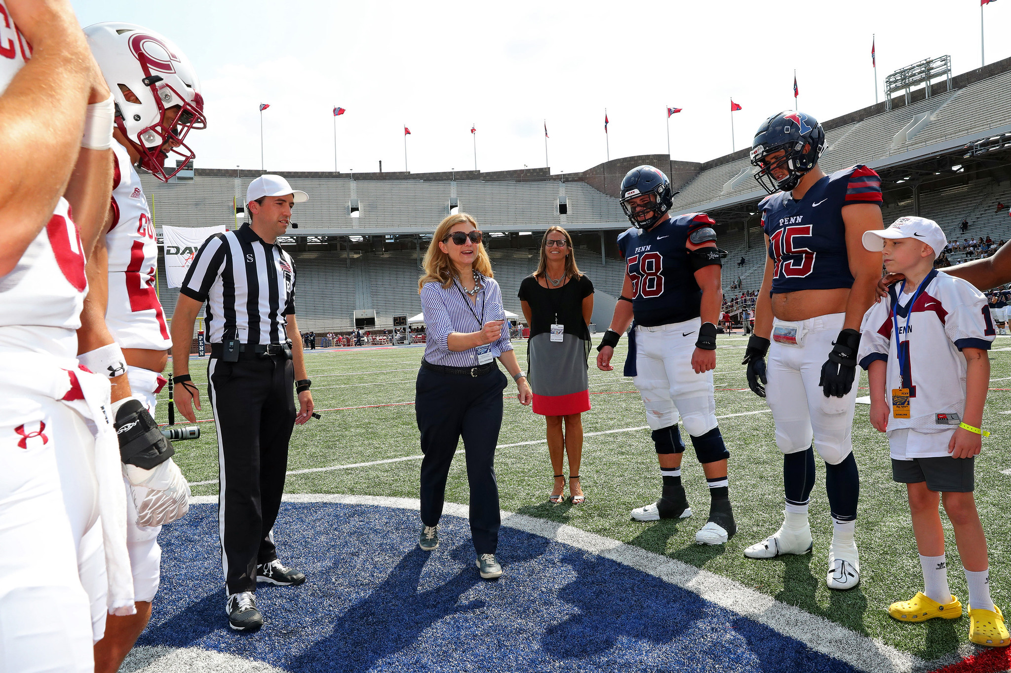 Liz Magill tossing a coin at the start of a football game on the field.