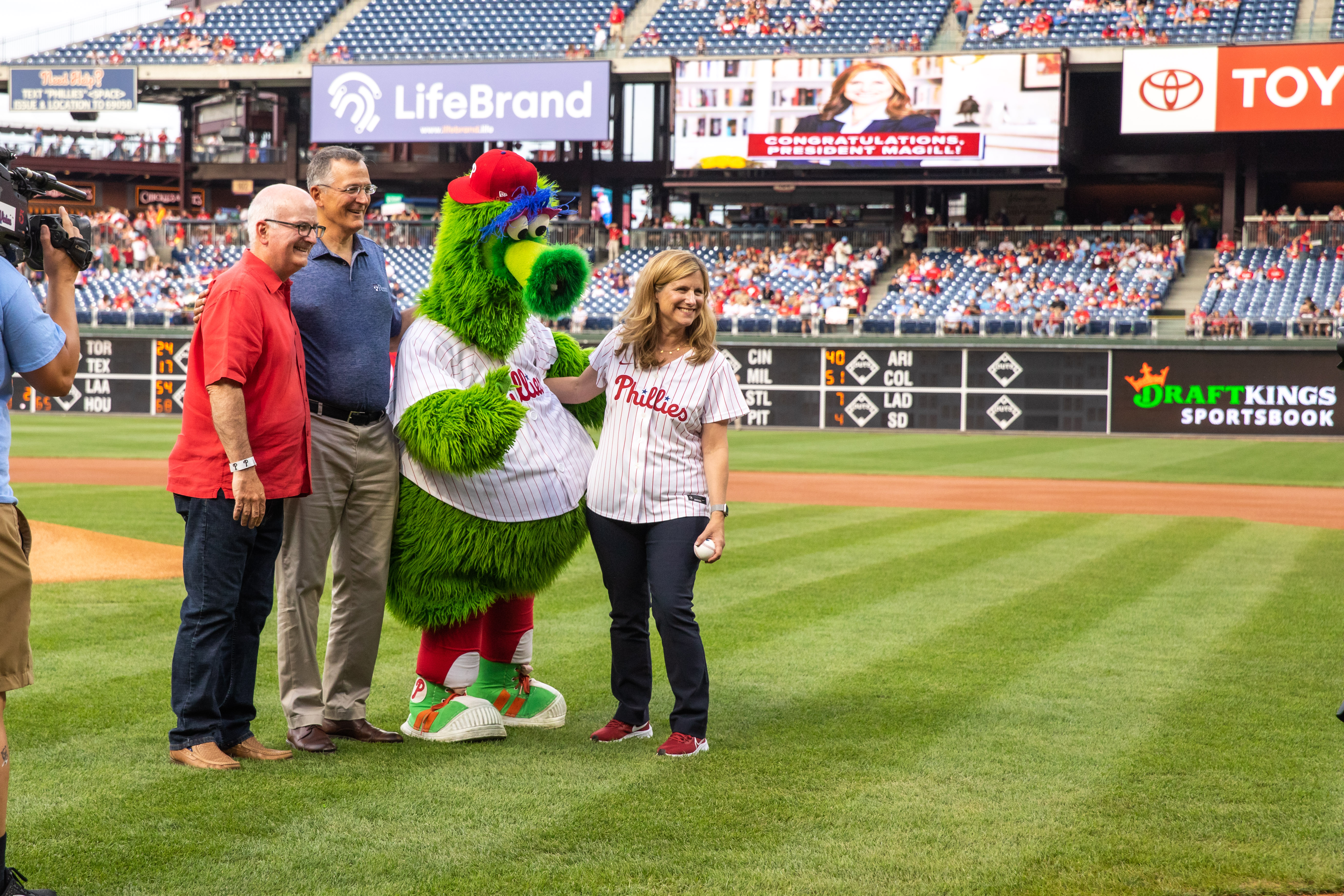 Liz Magill, the Philly Phanatic and two others at the pitchers mound on the field at the start of a Phillies game.