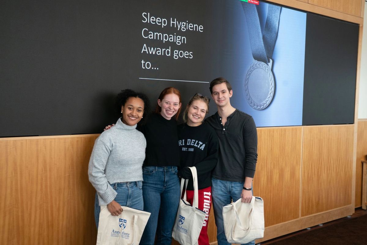 Chloe Hunter, Rachel Miller, Ally Riley, Jonah Charlton holding tote bags in front of a wall that reads “Sleep Hygiene Campaign Award goes to…”
