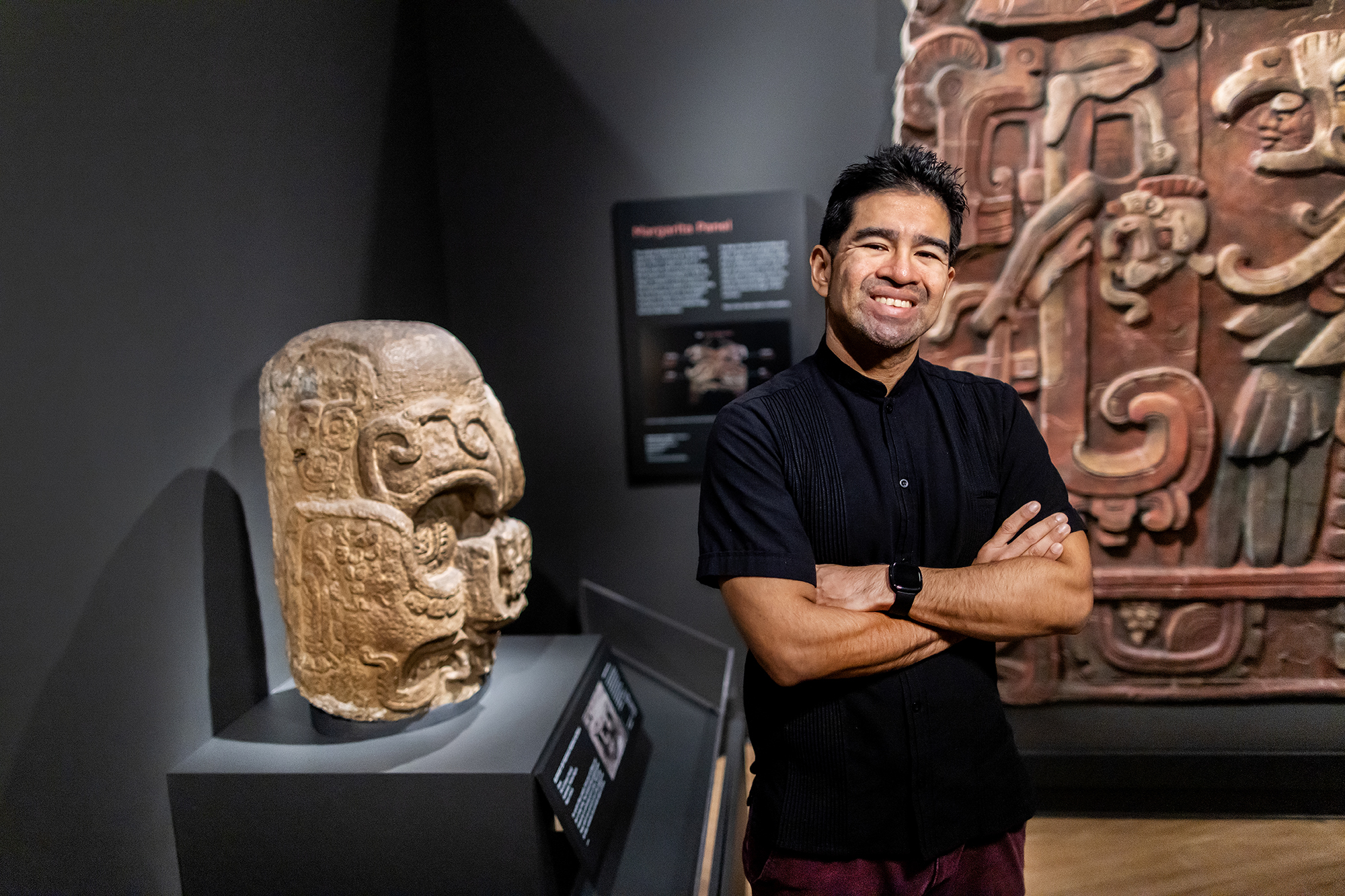 Francisco Diaz at the Penn Museum with carved stone reliefs made by his ancestors