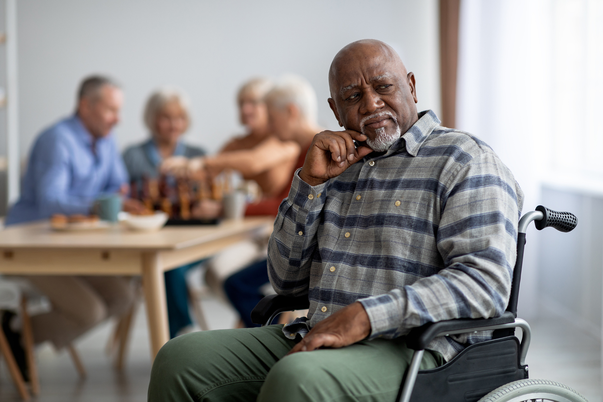 African American senior citizen in a wheelchair with a group of people in the background playing a game.