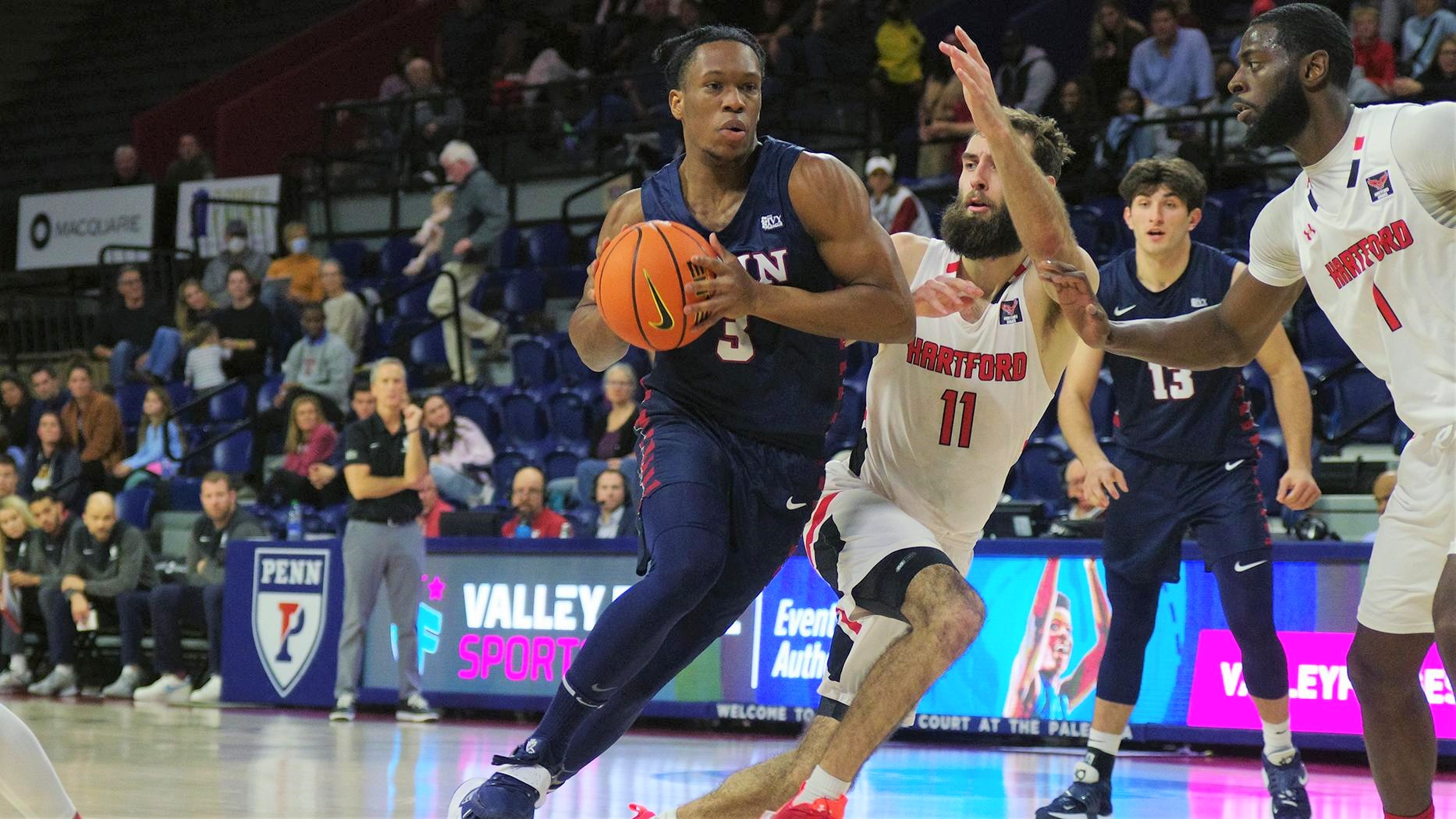 Dingle dribbles to the basket while a Hartford player tries to block him with arms and legs.