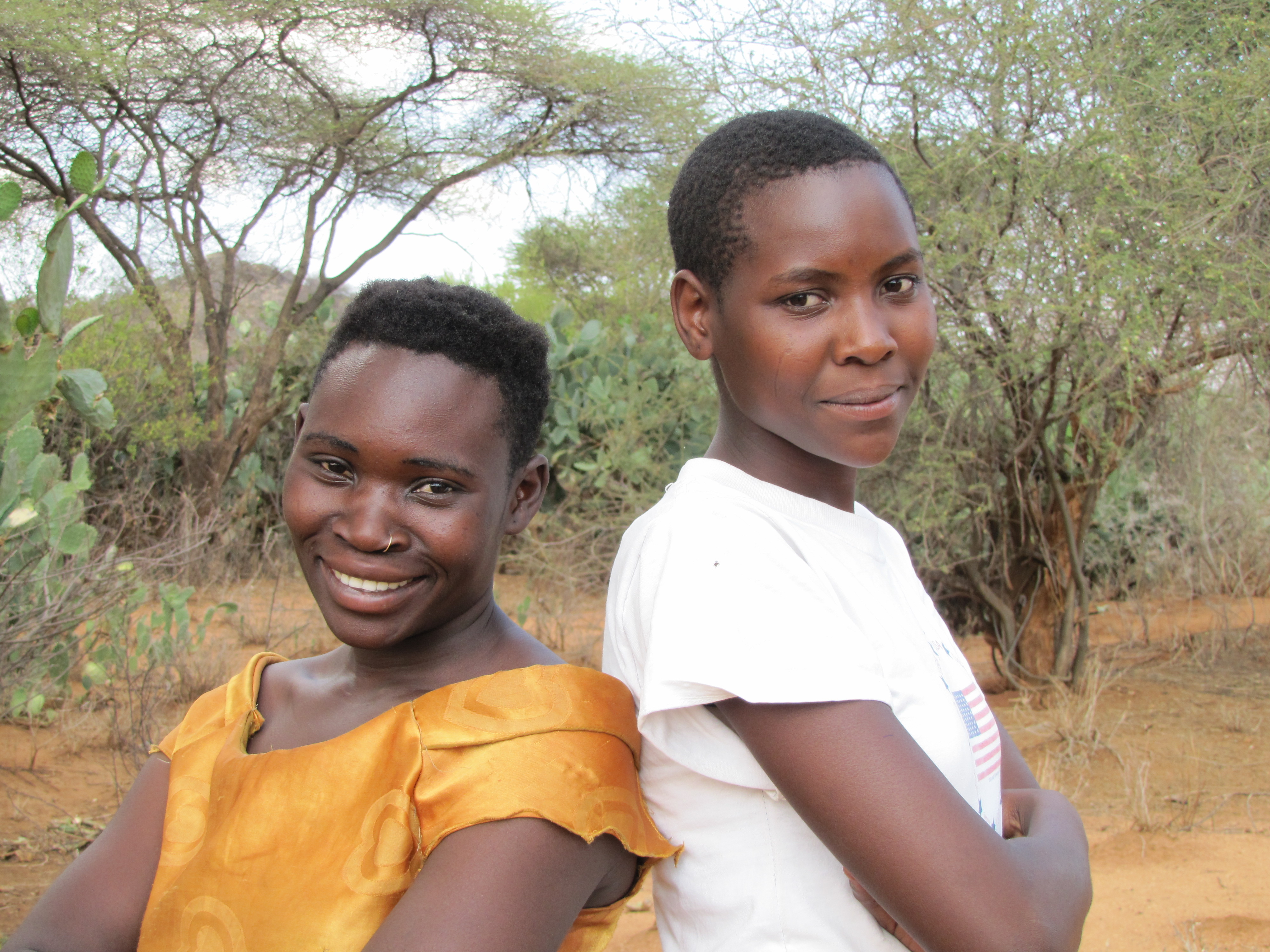 Two people from the Hadza group pose and smile outdoors