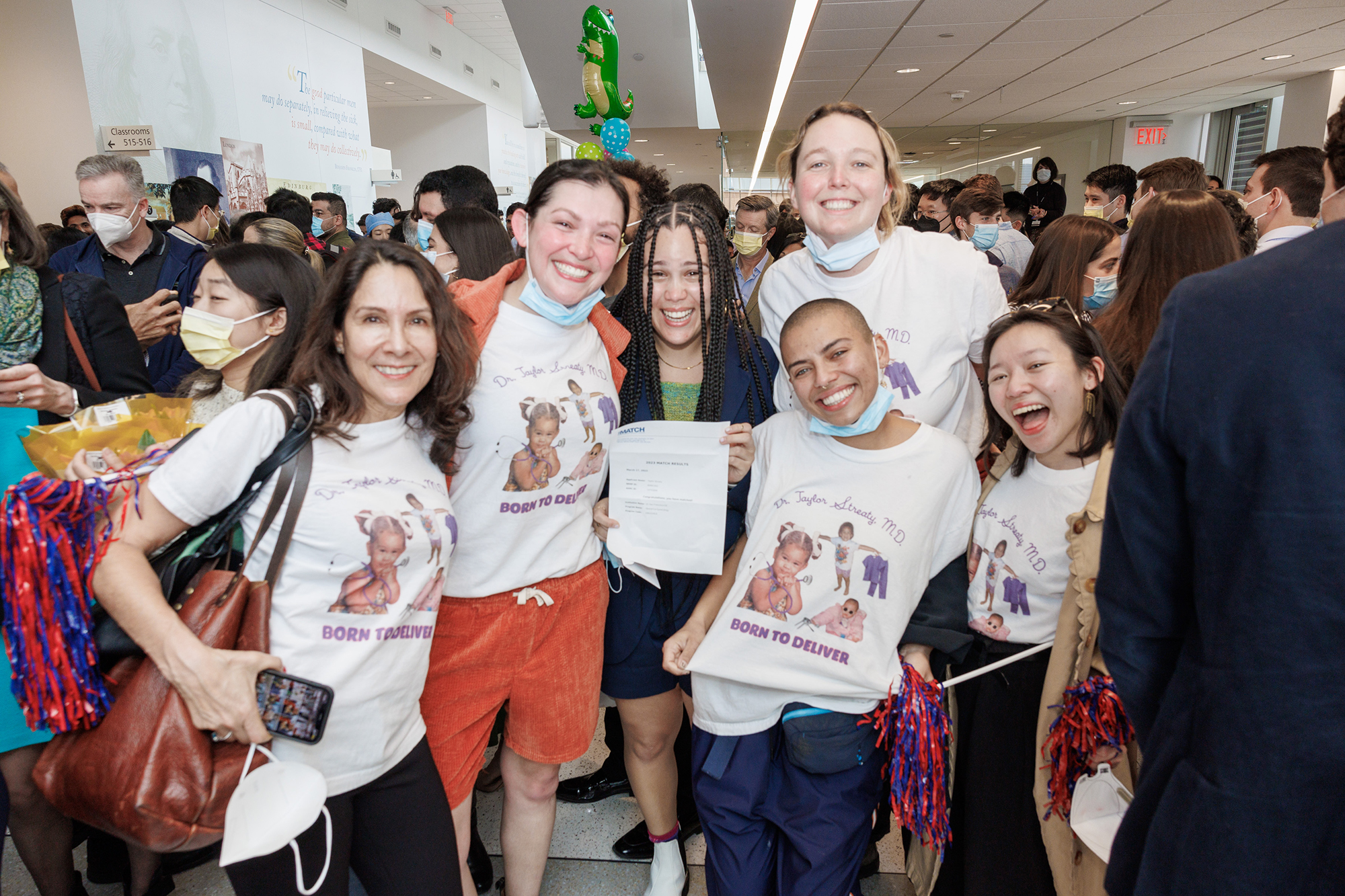 A group of people wearing matching Born to Deliver t-shirts in the atrium at Penn Med Match Day.