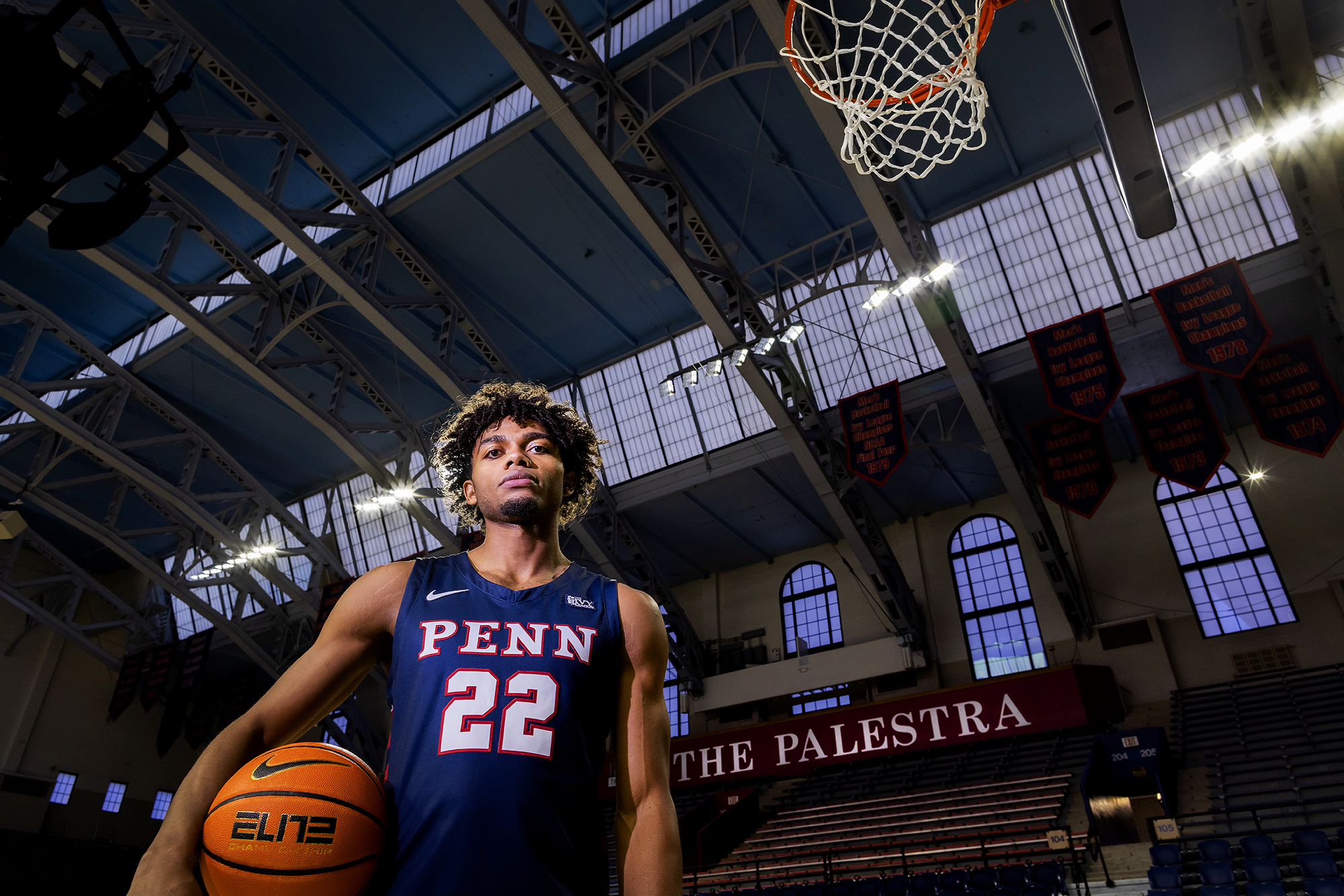 Monroe stands under the basketball hoop at the Palestra holding a basketball in his right arm.
