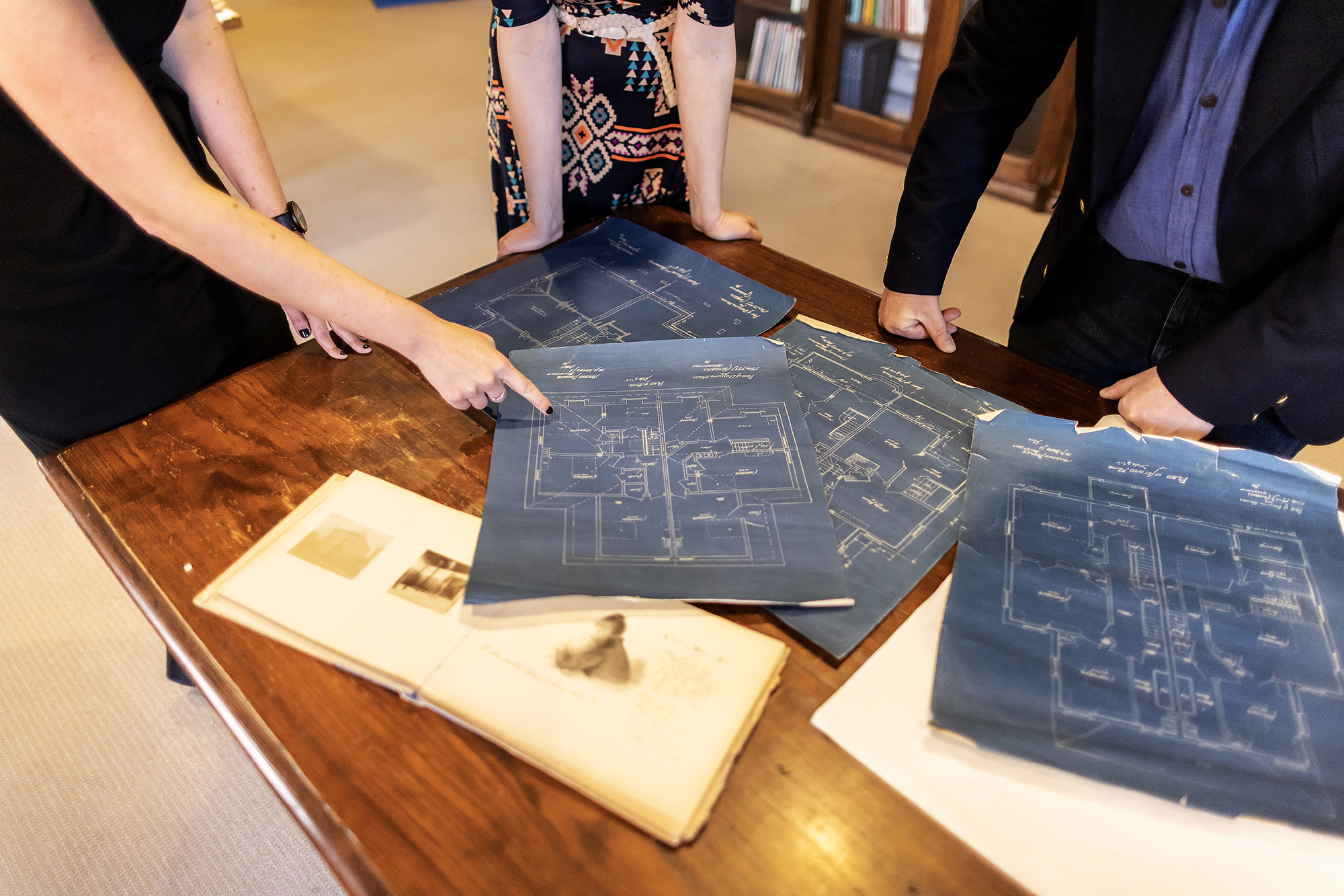 four blueprint architectural drawings on a table with an open photo book