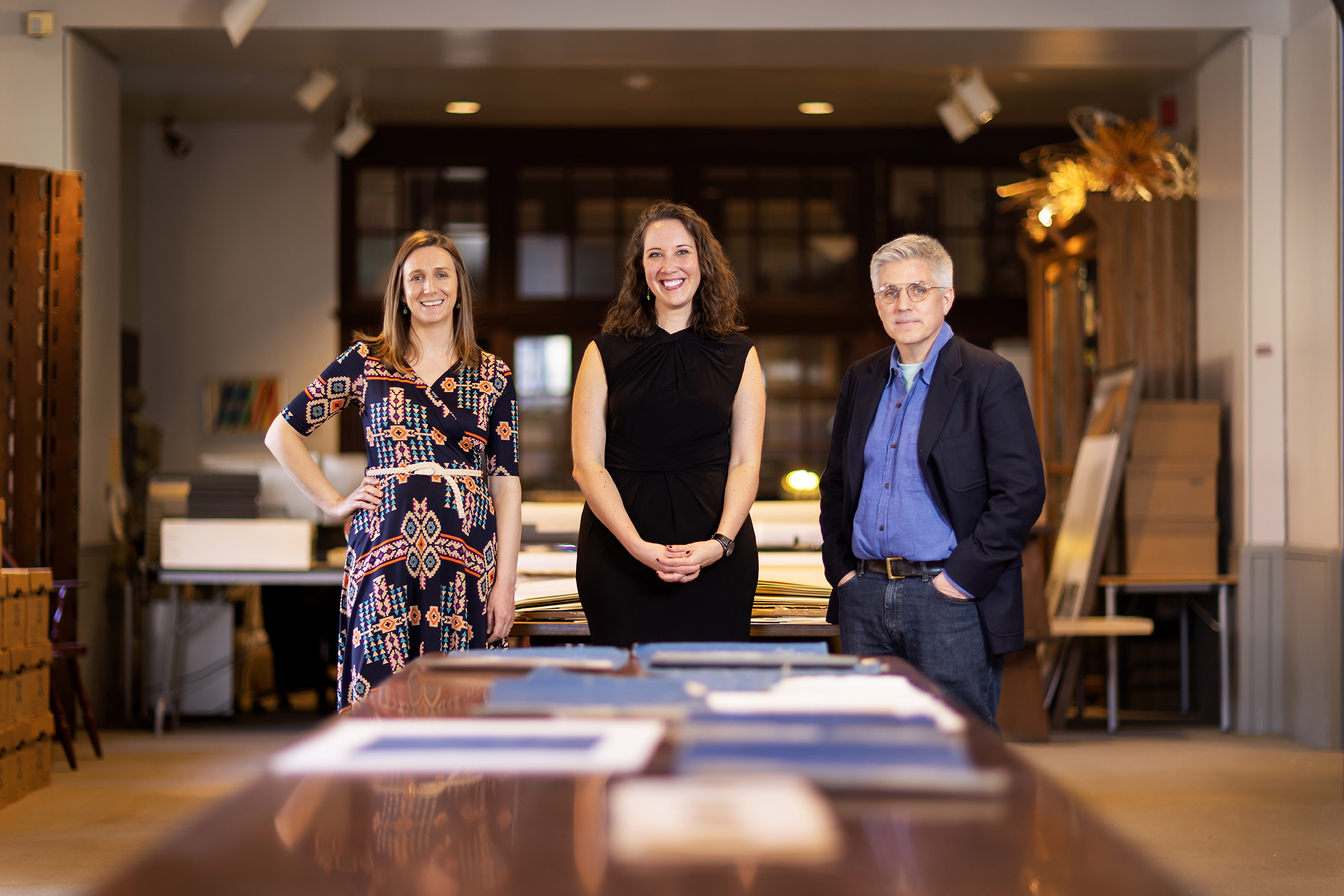 three people standing in front of a table in the archives