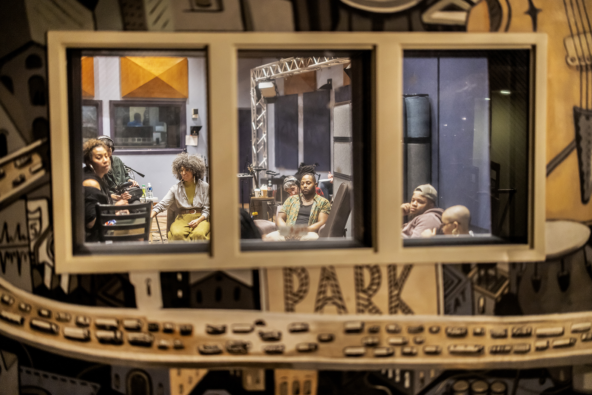 Members of a band seen through a window in WXPN’s recording studio.