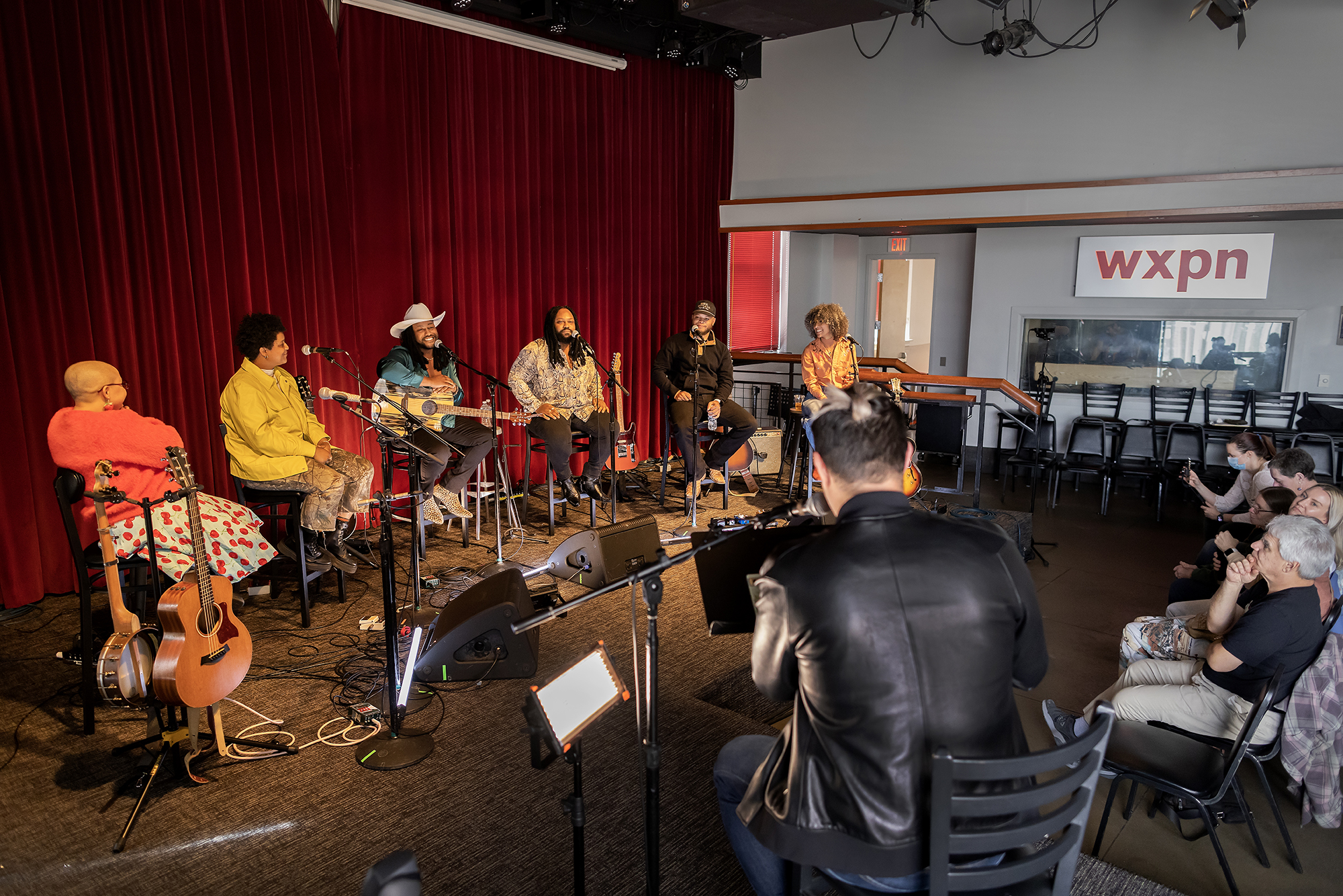 Members of a band seated in WXPN studio in front of a small audience.