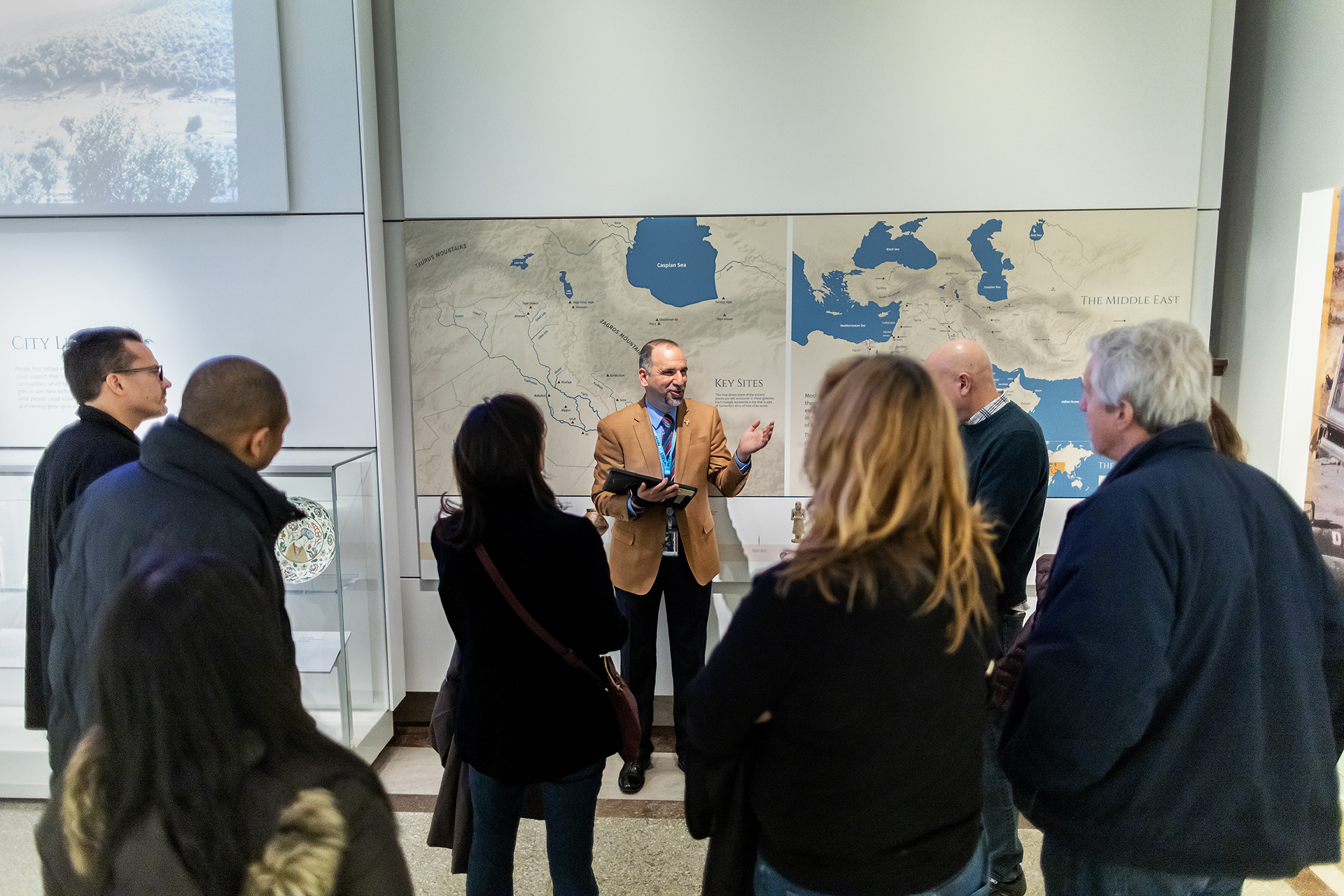 Yaroub Al-Obaidi gestures while speaking to a tour group in the Penn Museum's Middle East Galleries.