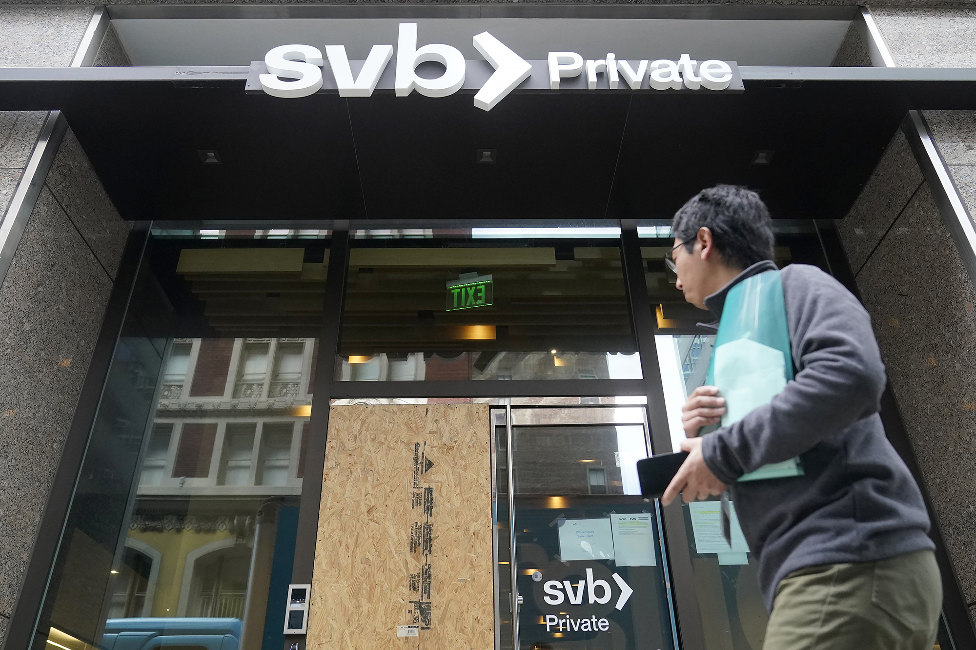 A person walking past a shuttered SVB branch.