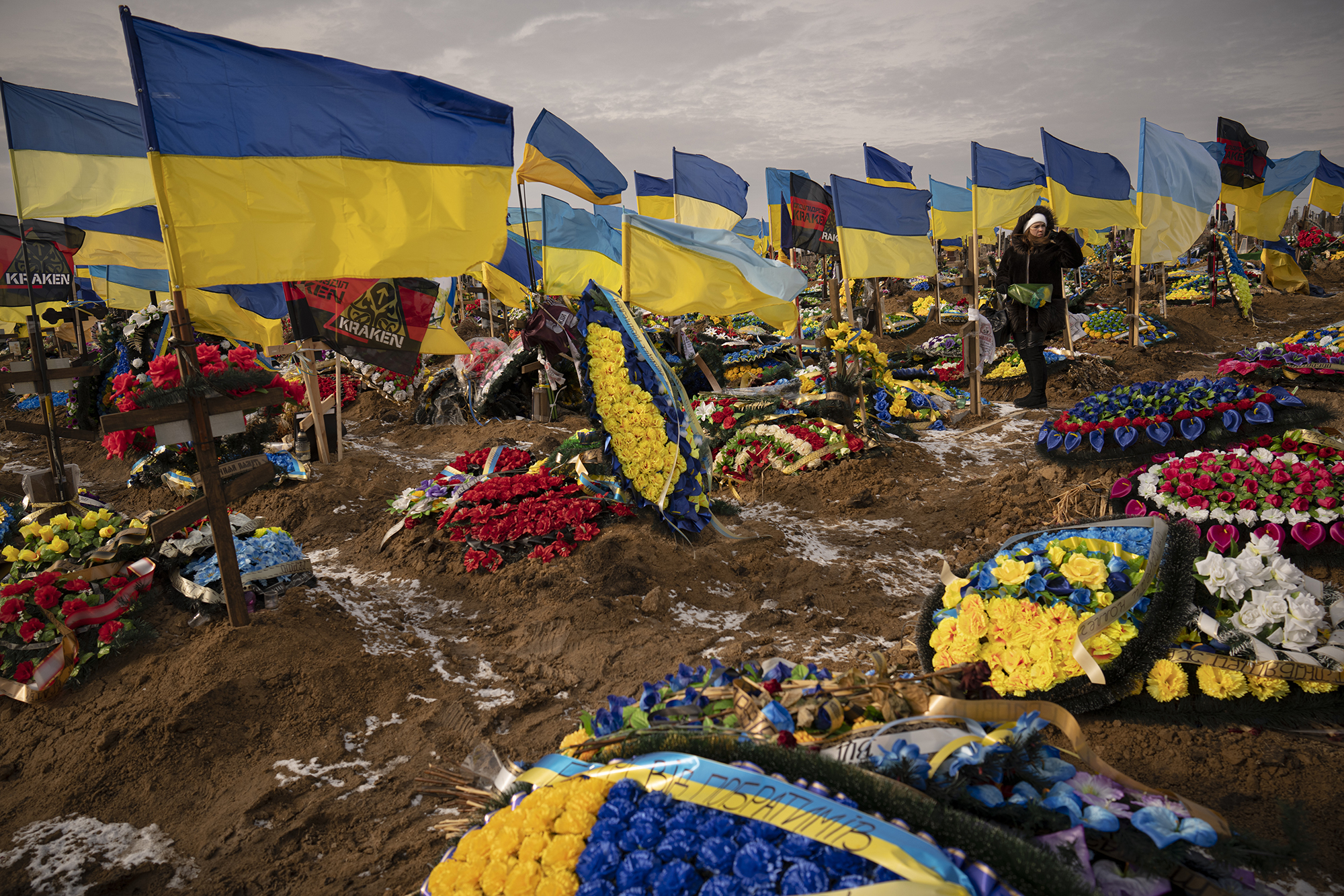 A graveyard is covered in Ukrainian flags and large displays of flowers.