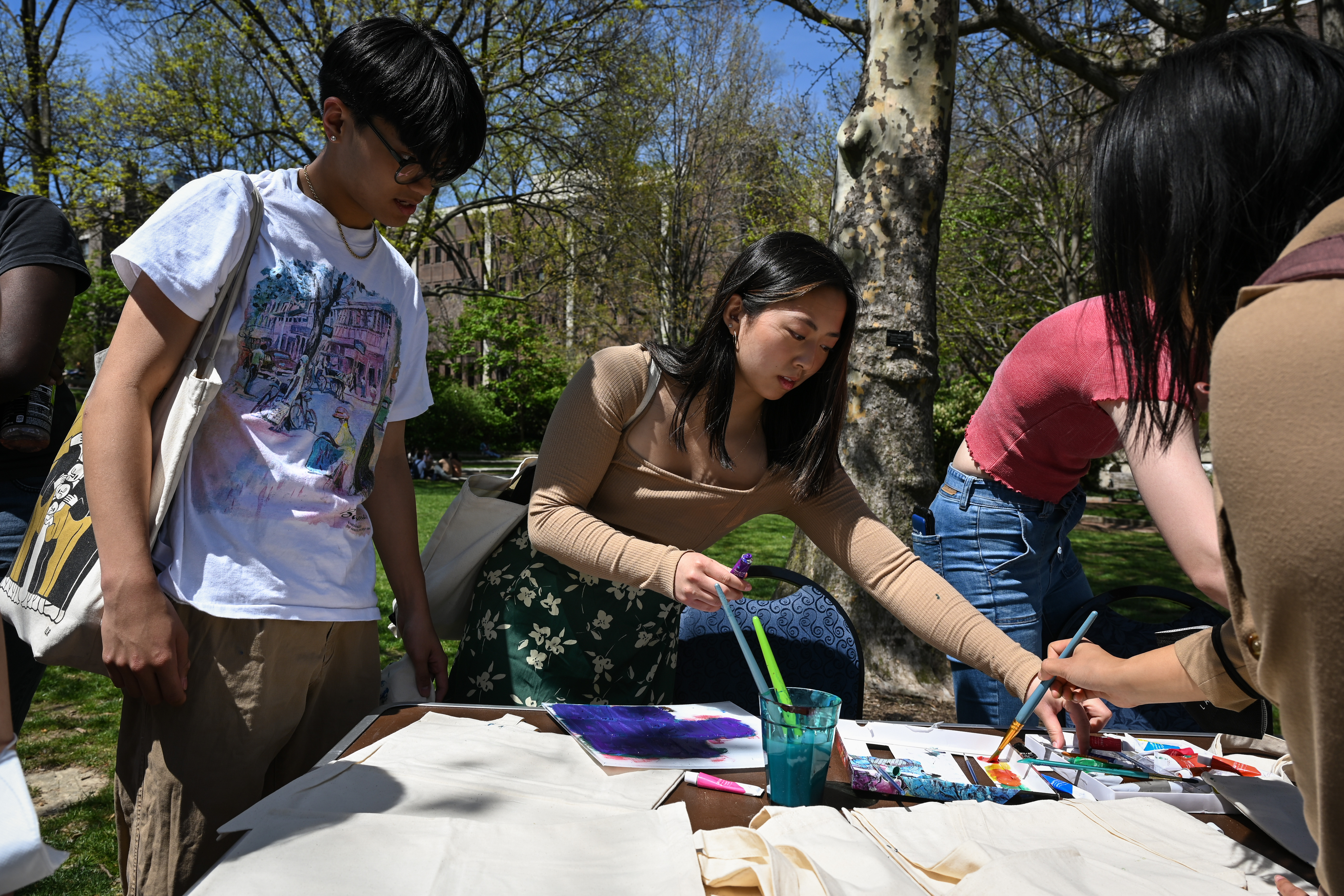 People participate in a painting activity at a table on Penn's campus