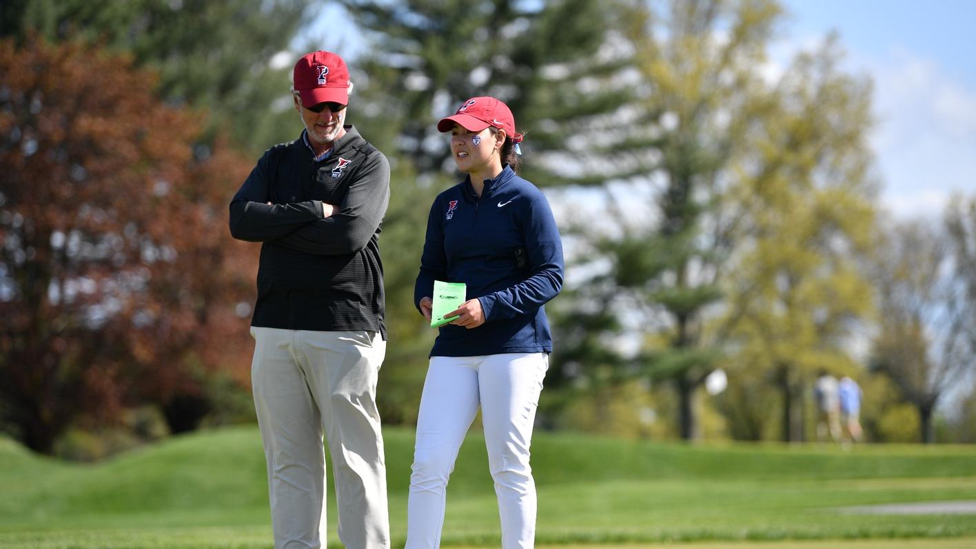 Mark Anderson and a Penn athlete talking on a golf course.