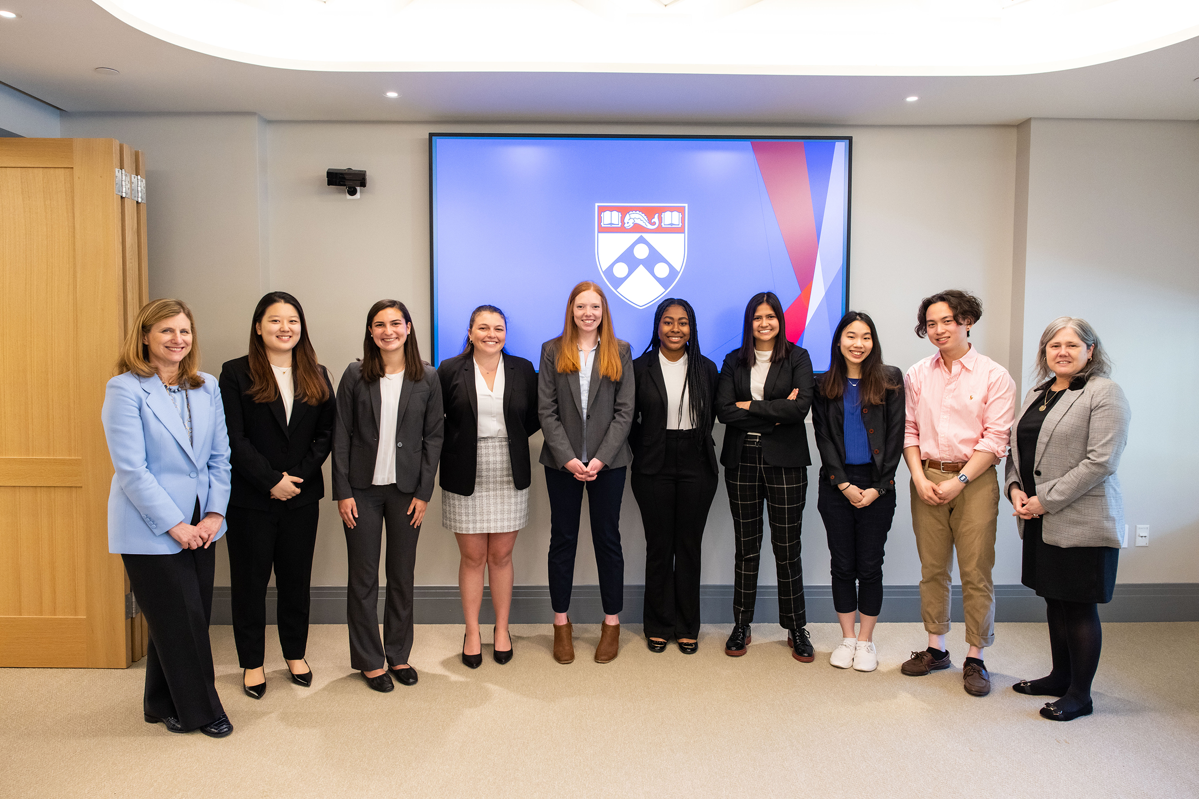 Magill, Winkelstein and PIP PEP awardees smile for a photo in front of a screen with Penn symbol