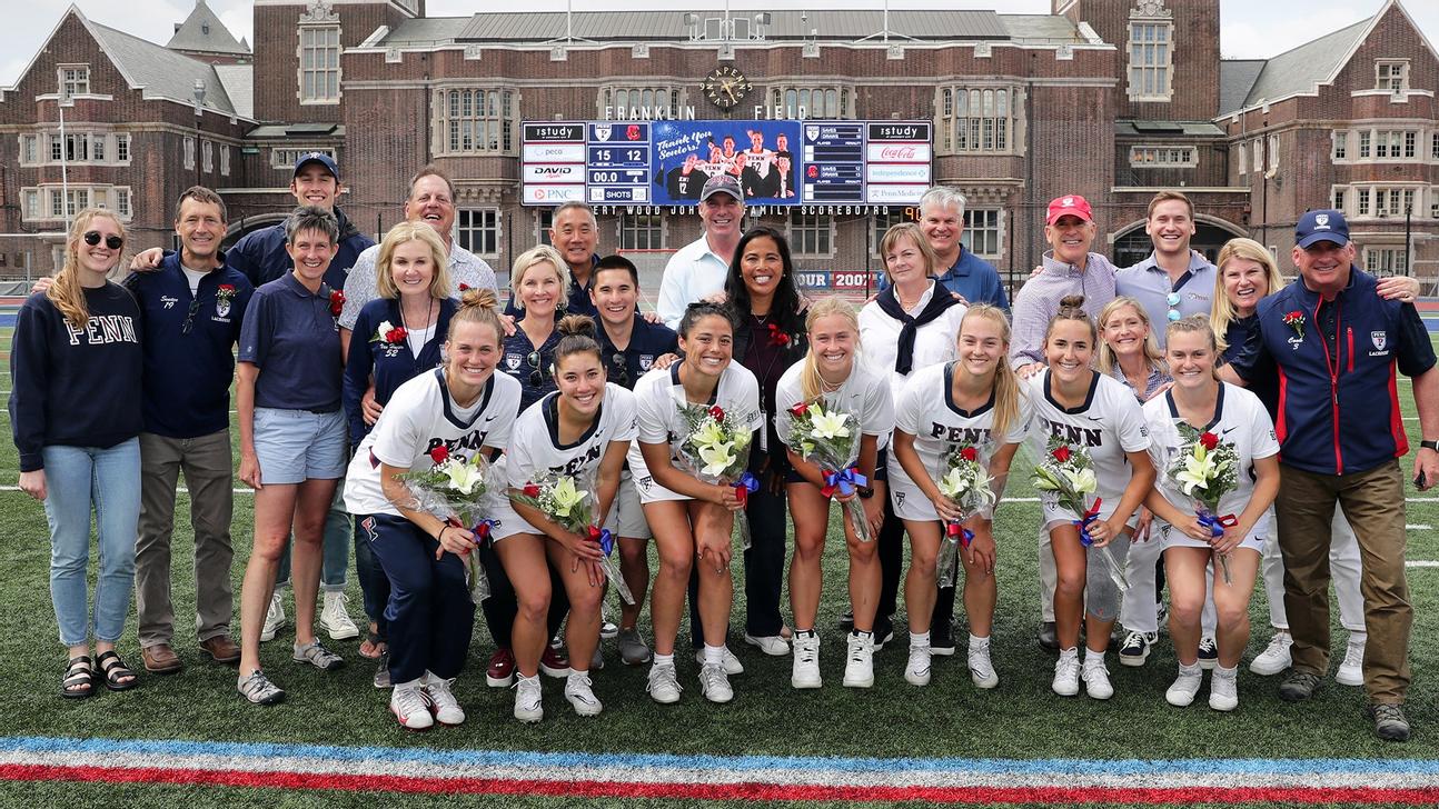 Women's lacrosse team seniors jubilantly smiling in a huddle with family and coaches.