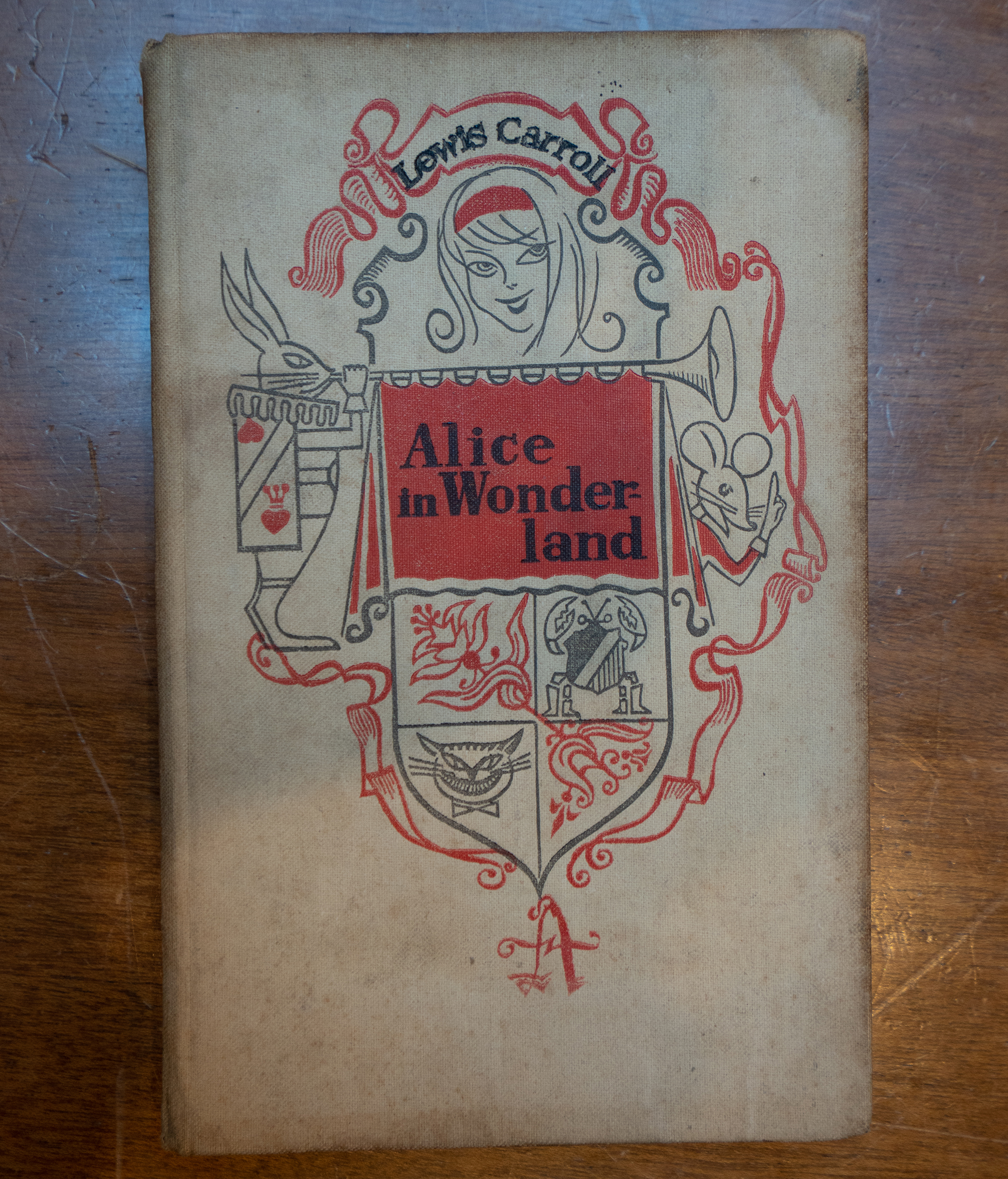A copy of 'Alice in Wonderland' lies on a wooden table