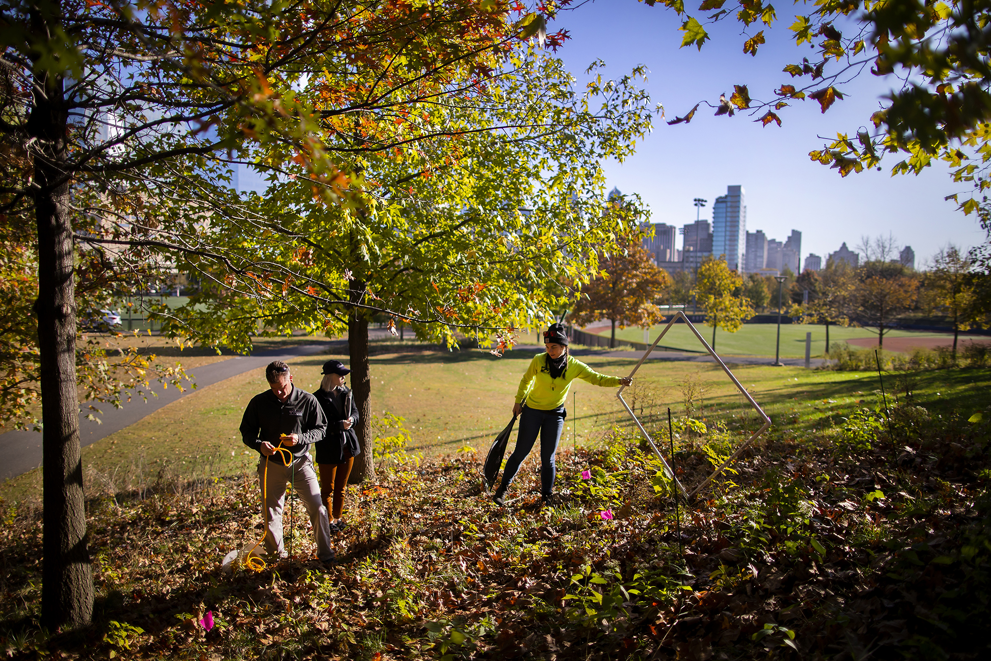 facility personnel working with fallen leaves at penn park