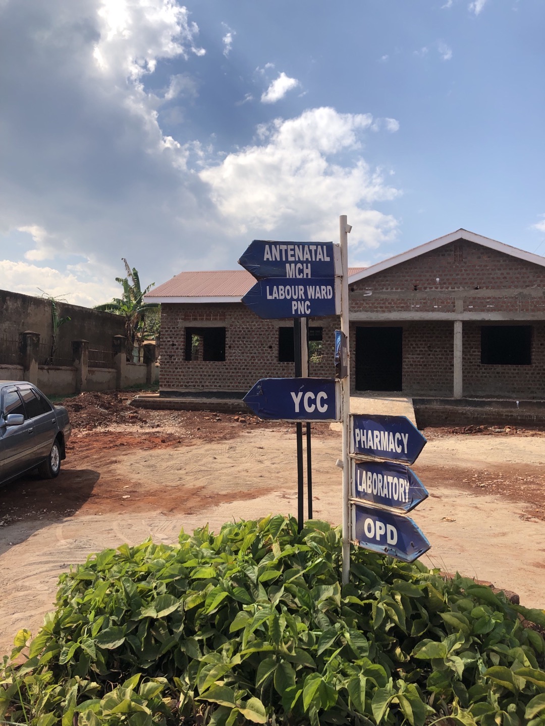 Image of a brick building with signs out front pointing to "Antenatal MCH, Labour ward PNC, YCC, Pharmacy, Laboratory, OPD"
