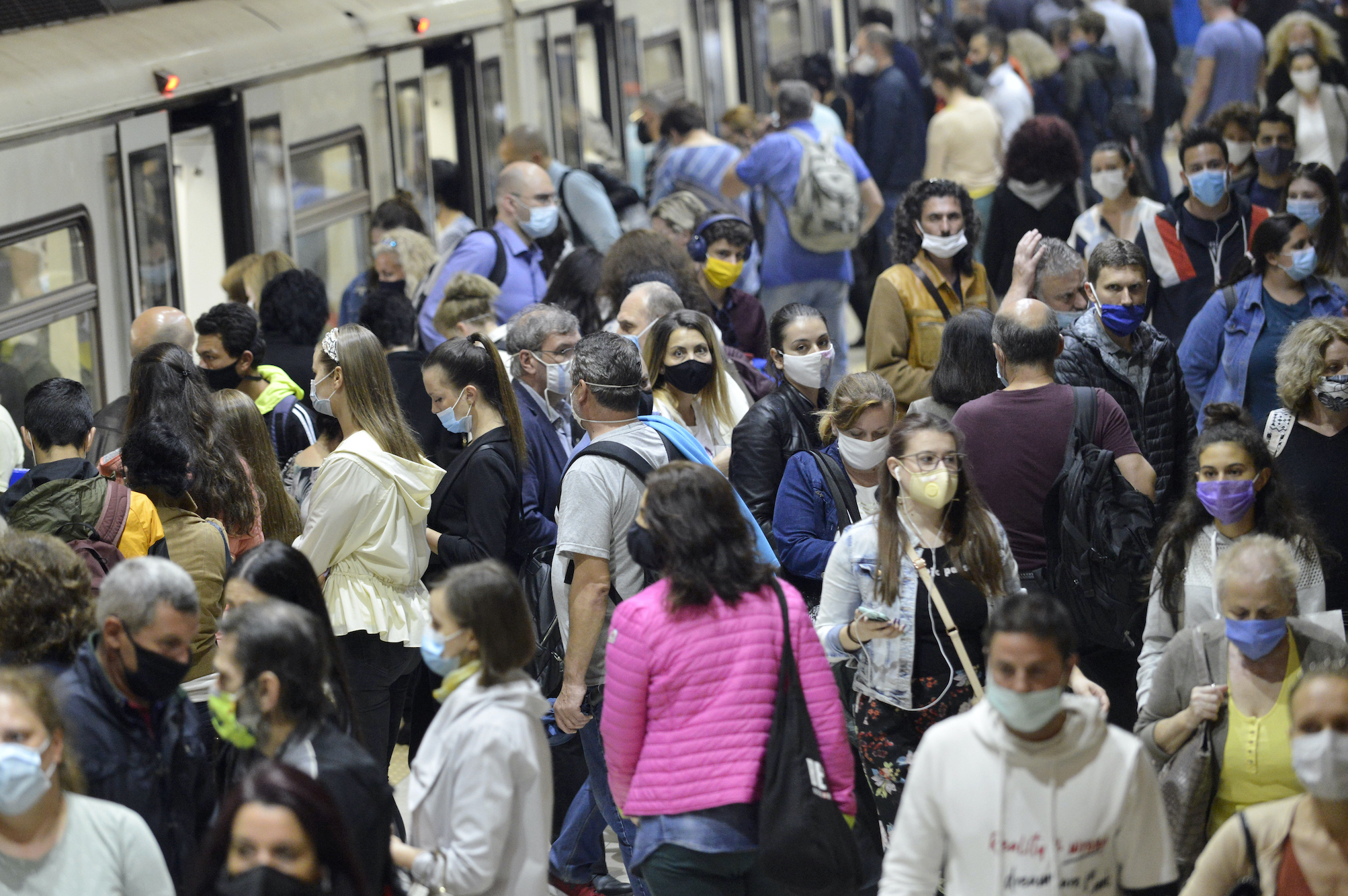 Subway train passengers with protective masks crowding to get on and off subway station platform on Metro station.