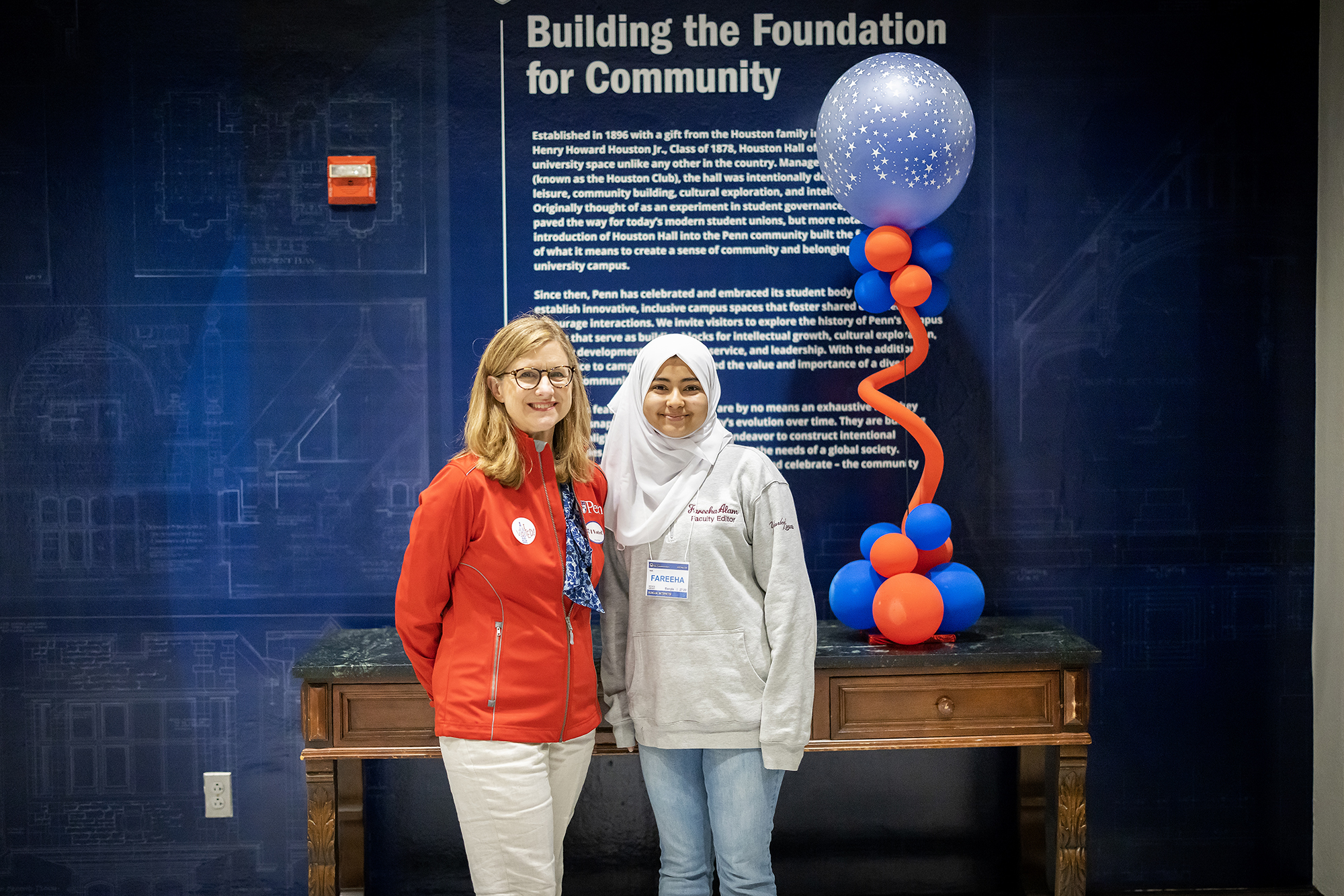 Penn President Liz Magill stands with Fareeha Alam in front of a wall that reads Building the Foundation for Community.