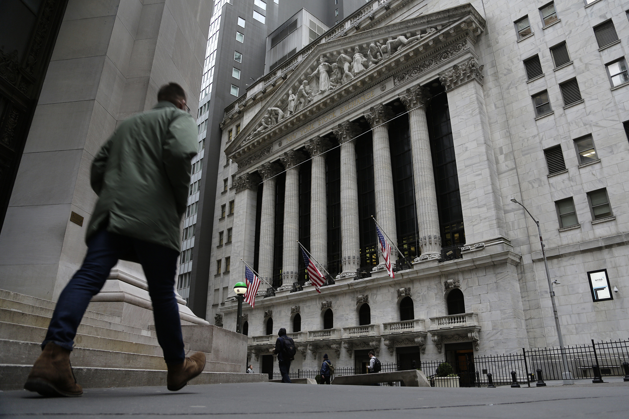 A person is seen walking in front of the New York Stock Exchange on Wall Street.