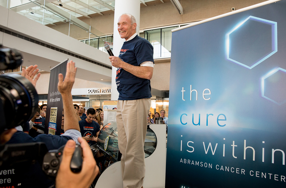 Carl June with a microphone in the Penn Medicine atrium with the celebratory flash mob.