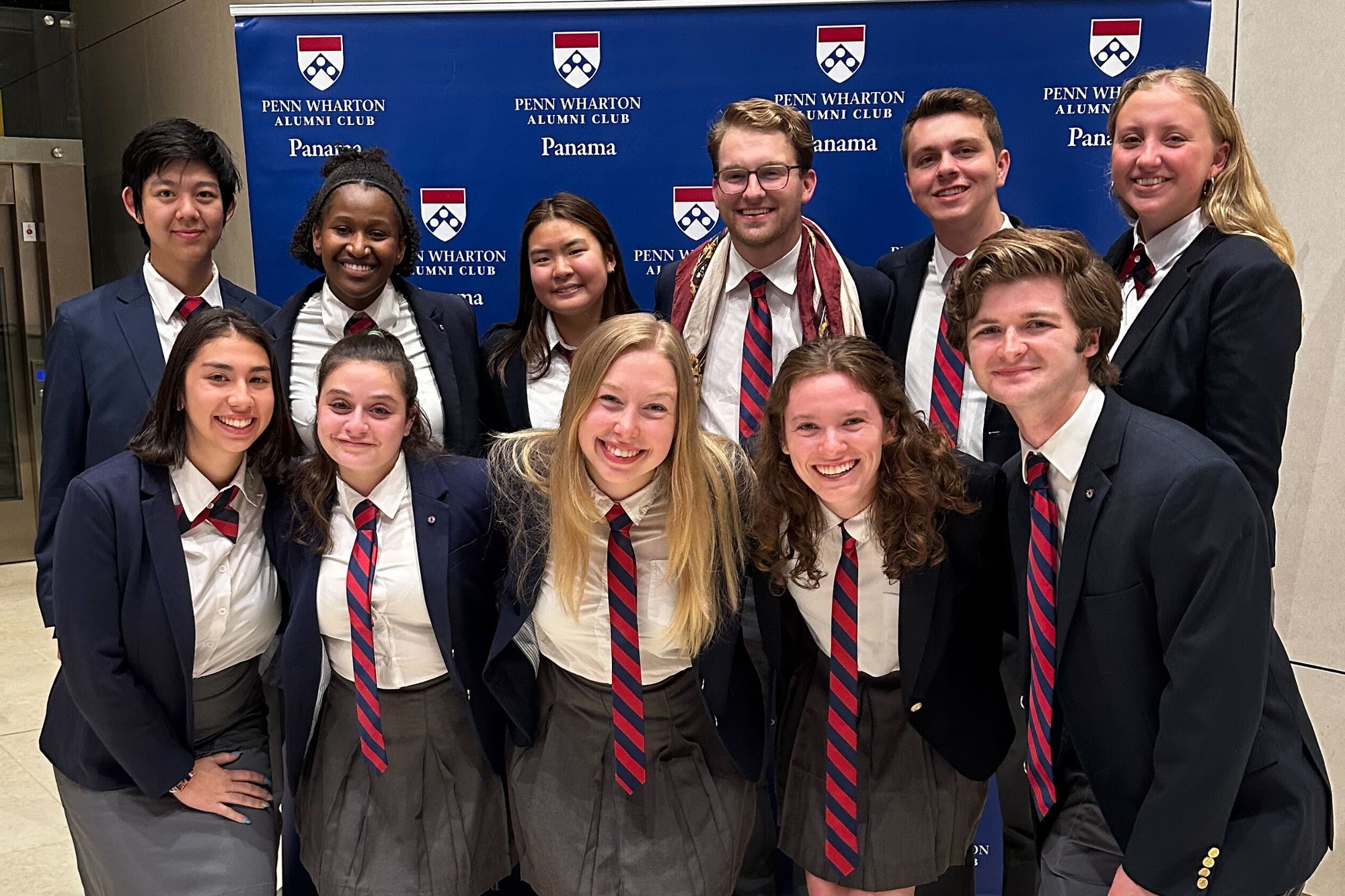 11 members of Penn’s Glee Club in front of a Penn-themed step and repeat.