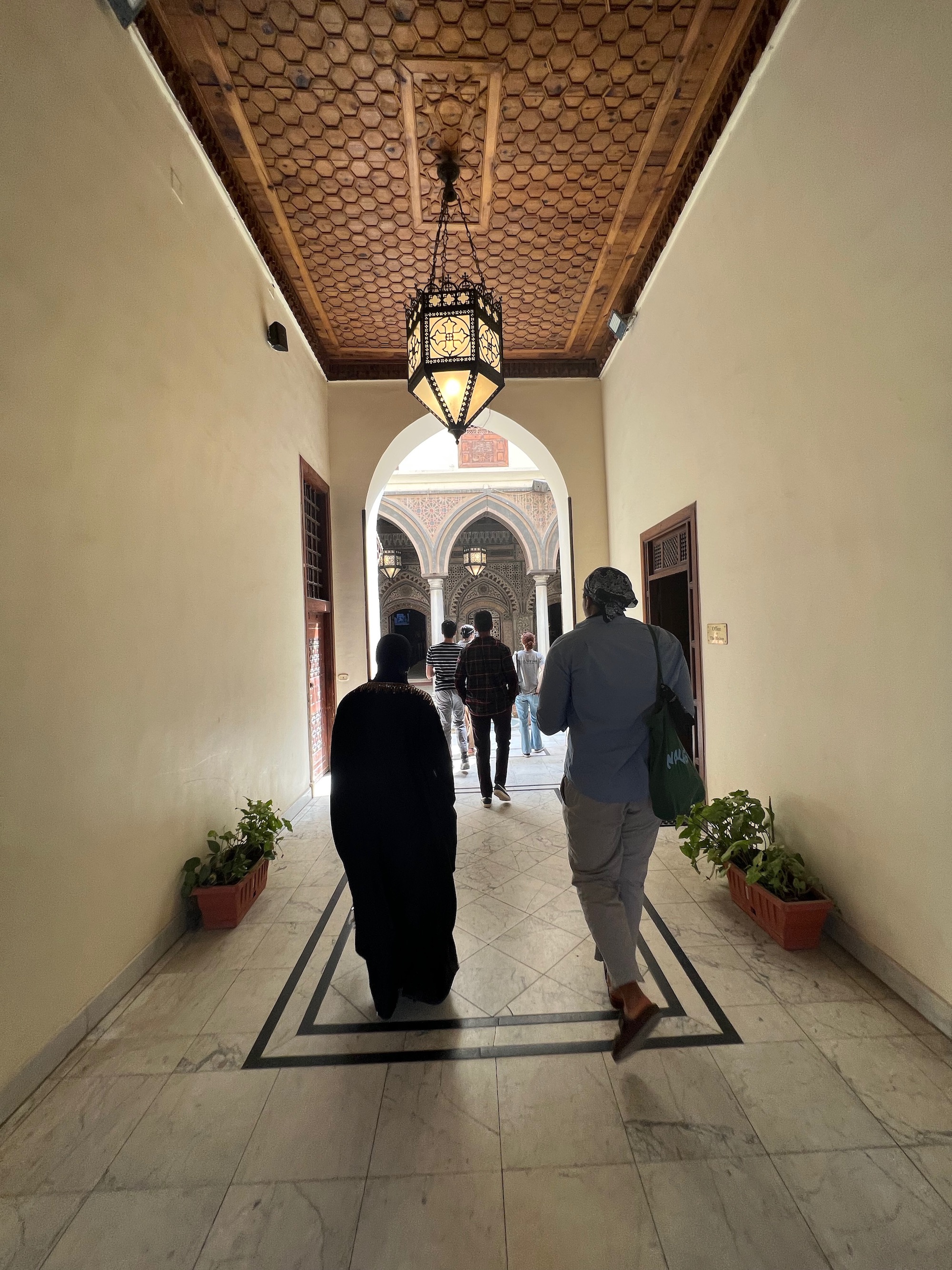 An interior shot of a group of people walking towards a courtyard. 