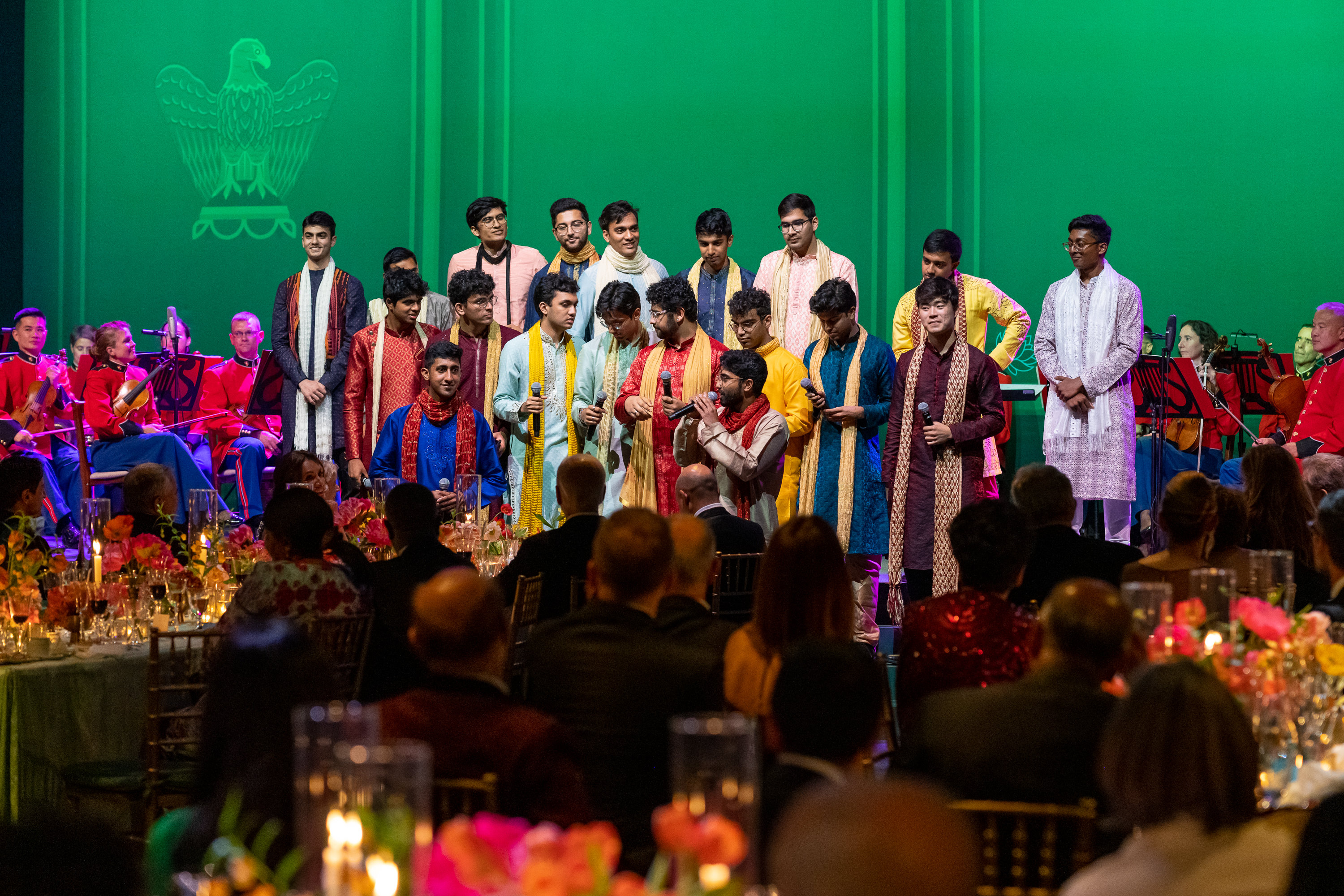 19 students dressed in formal traditional Indian clothing performing at dinner