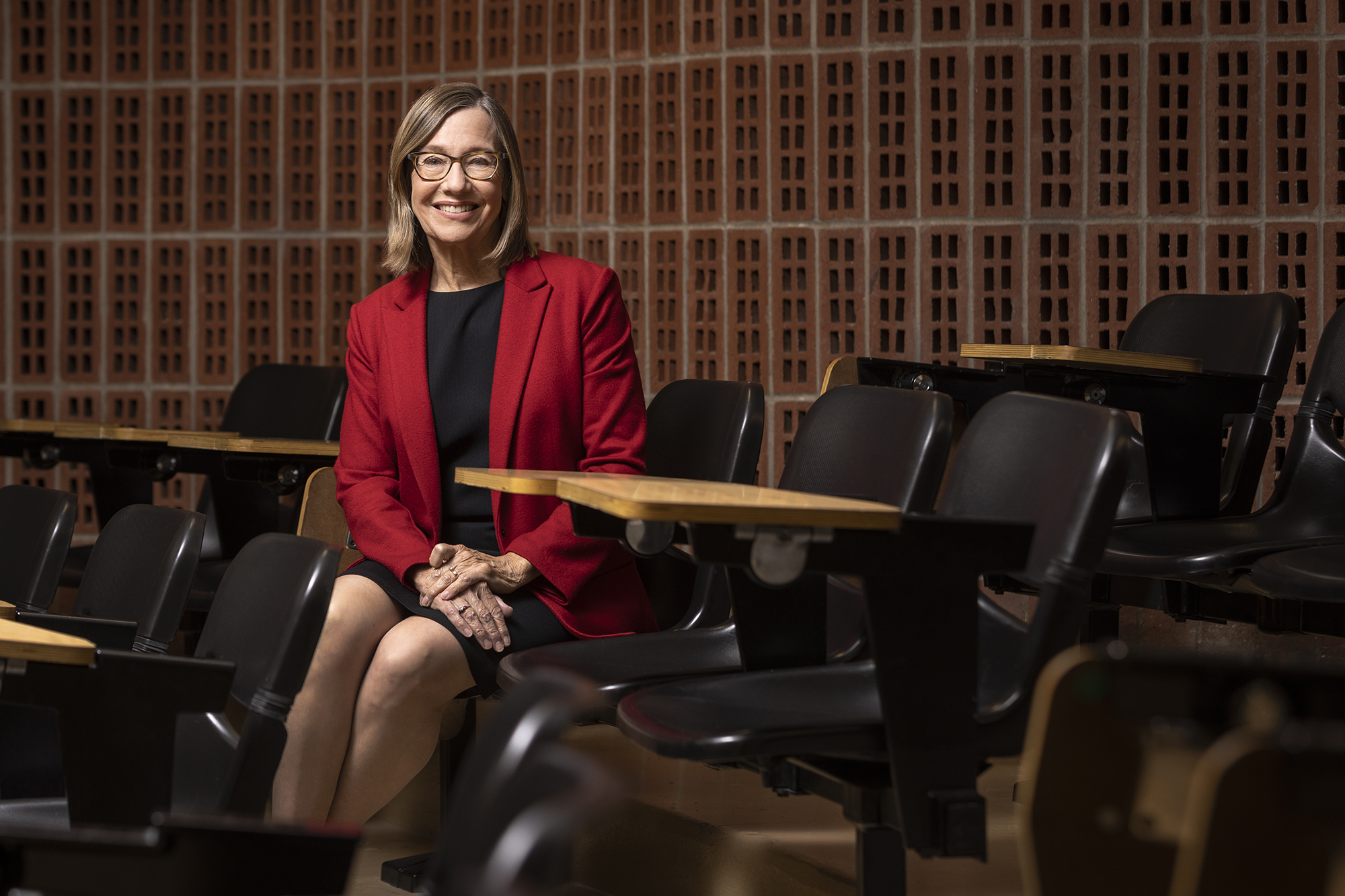 The outgoing dean sits in a chair in a lecture hall in the Graduate School of Education