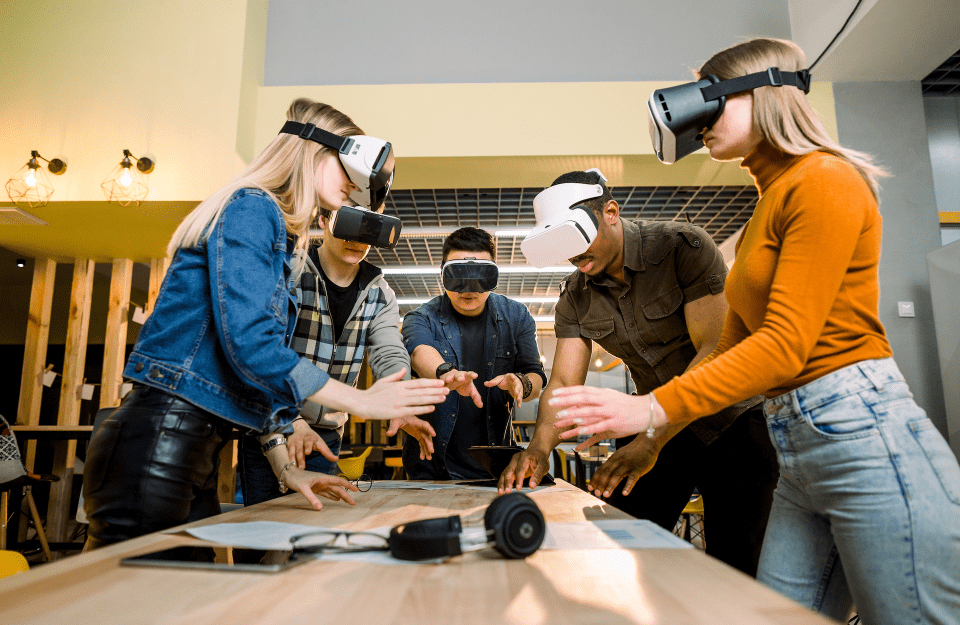 A group of people standing at a table wearing VR headsets.