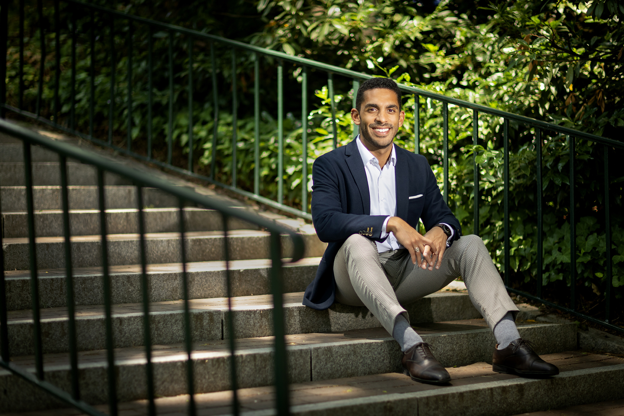 Rich Lizardo sits on concrete stairs in front of greenery on Penn campus.