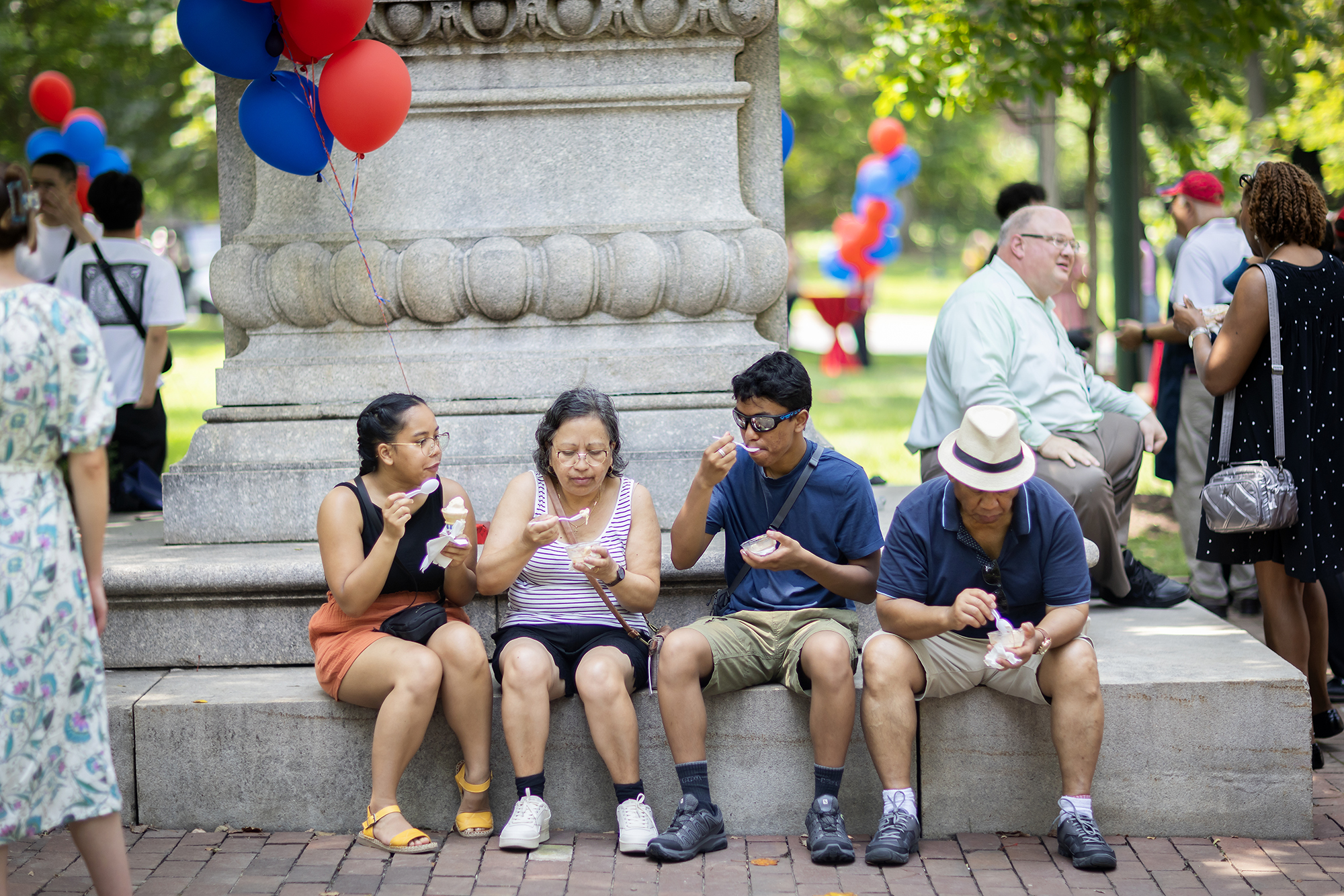 Four people eating ice cream by the Ben Franklin statue on College Green.