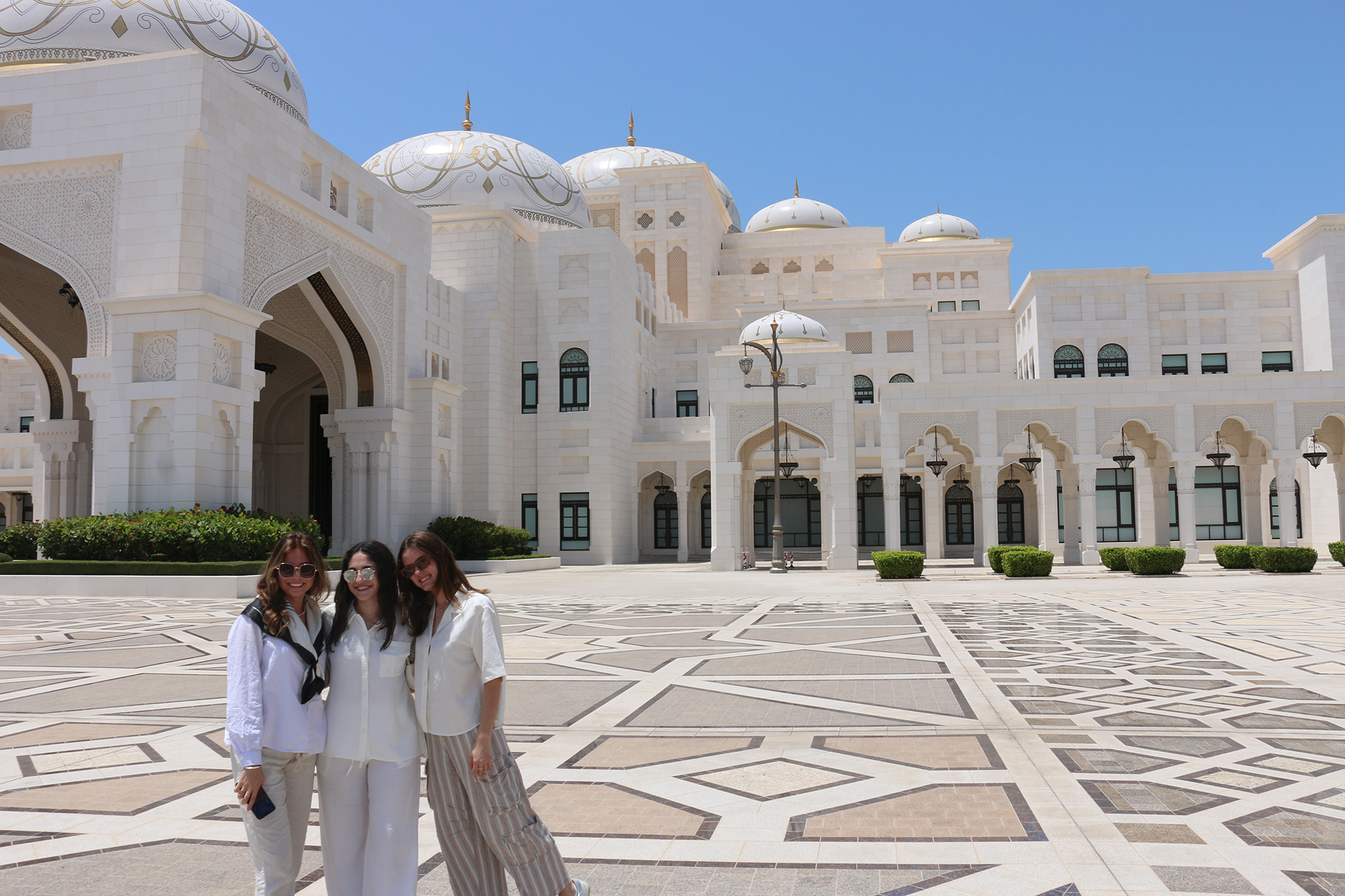 Three students in a sunlit courtyard in the UAE.