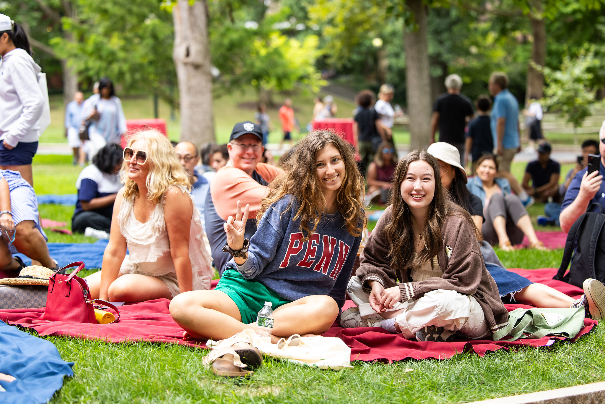 Students and families sitting on red and blue tablecloths on College Green