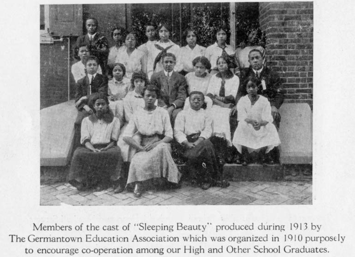 Three rows of students in front of a brick building. The caption reads "Members of the cast of 'Sleeping Beauty' produced during 1913 by The Germantown Education Association which was organized in 1910 purposely to encourage cooperation among our High and Other School Graudates."