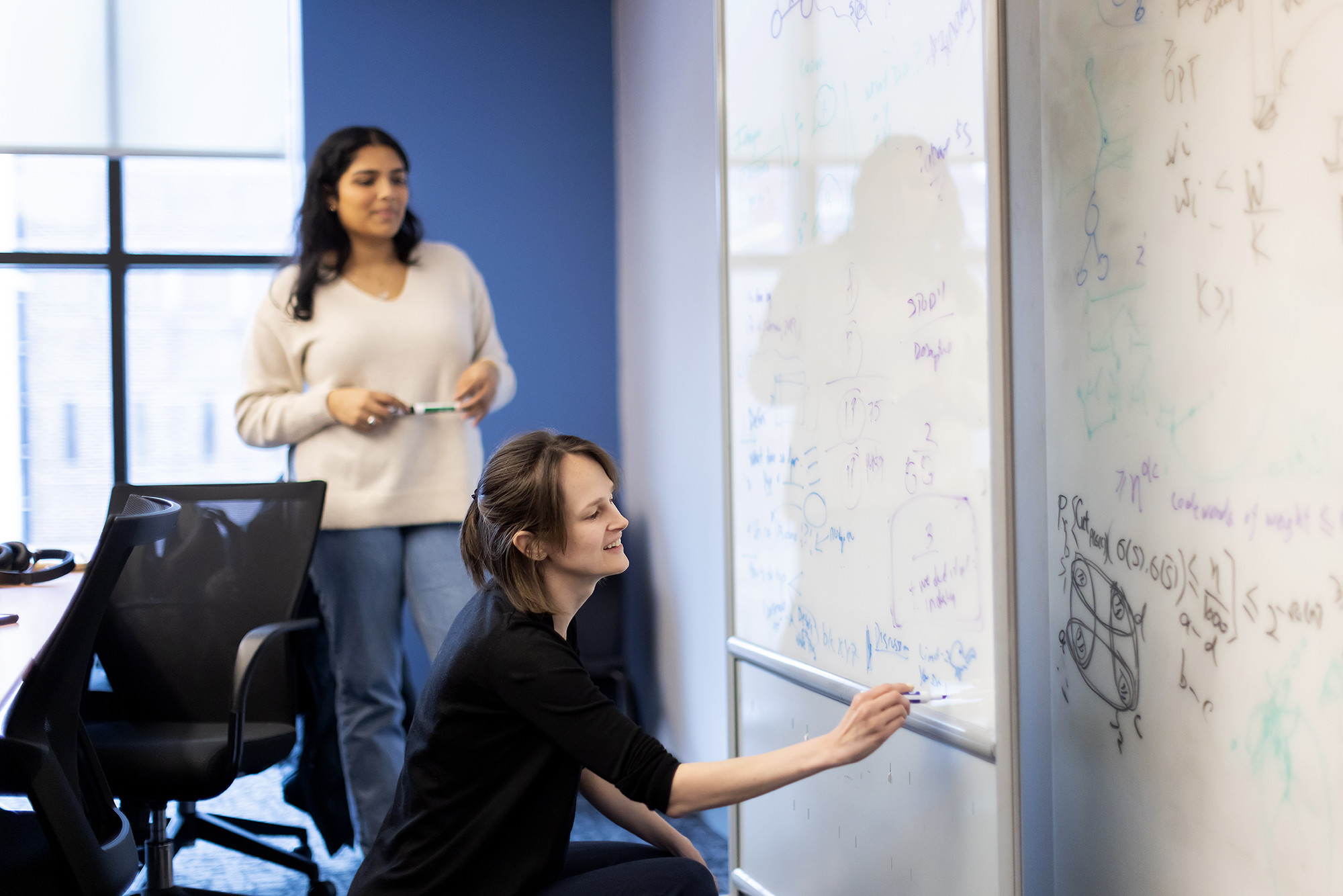 Linnea Gandhi of the Wharton School and research assistant Anoushka Kiyawat using a white board